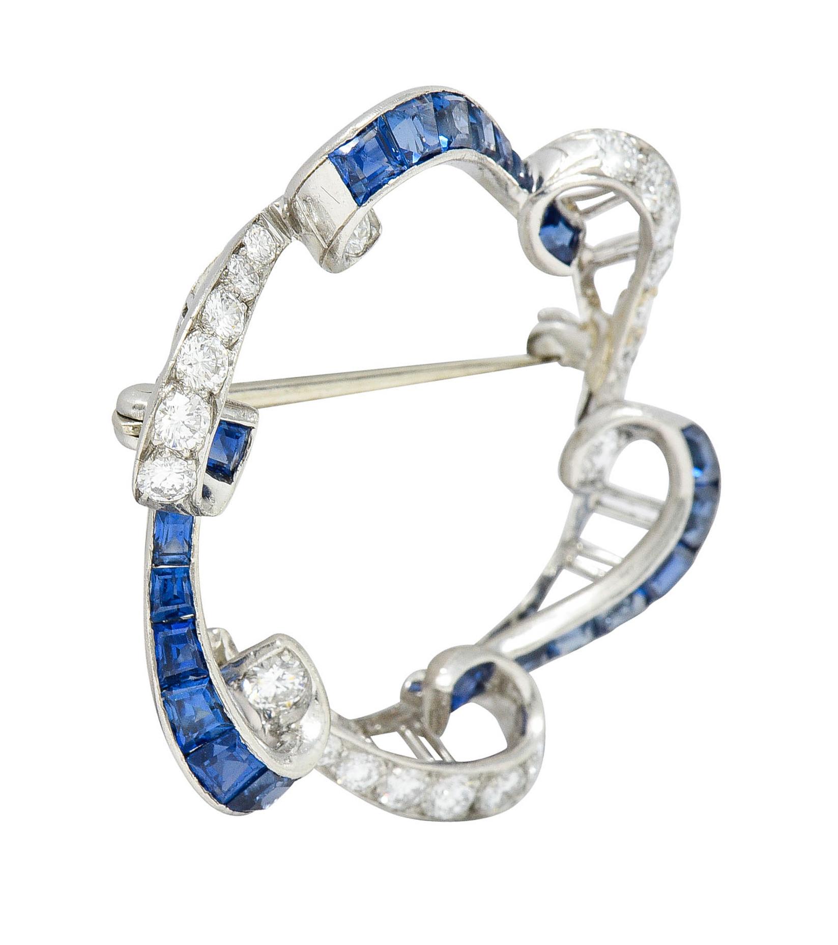 Wreath style brooch is comprised of ribbon-like scrolls - alternating sections of sapphires and diamonds

Sapphires are a very well matched royal blue while weighing approximately 2.70 carats

Round brilliant cut diamonds weigh in total