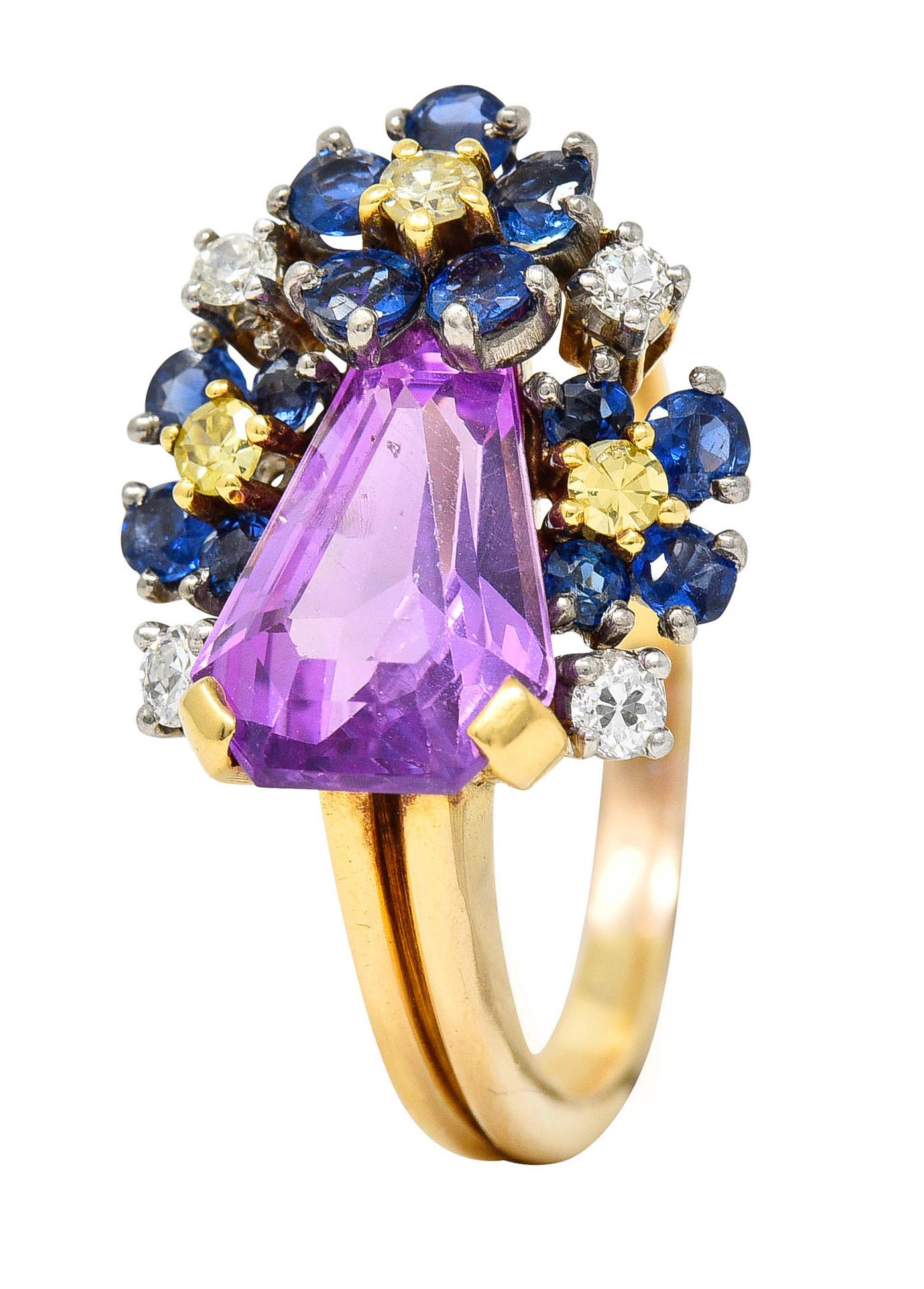 Asymmetrical cluster ring features a shield cut lavender sapphire

Medium light pinkish purple in color while weighing approximately 3.40 carats

Surrounded by florals comprised of royal blue sapphires weighing in total approximately 0.56
