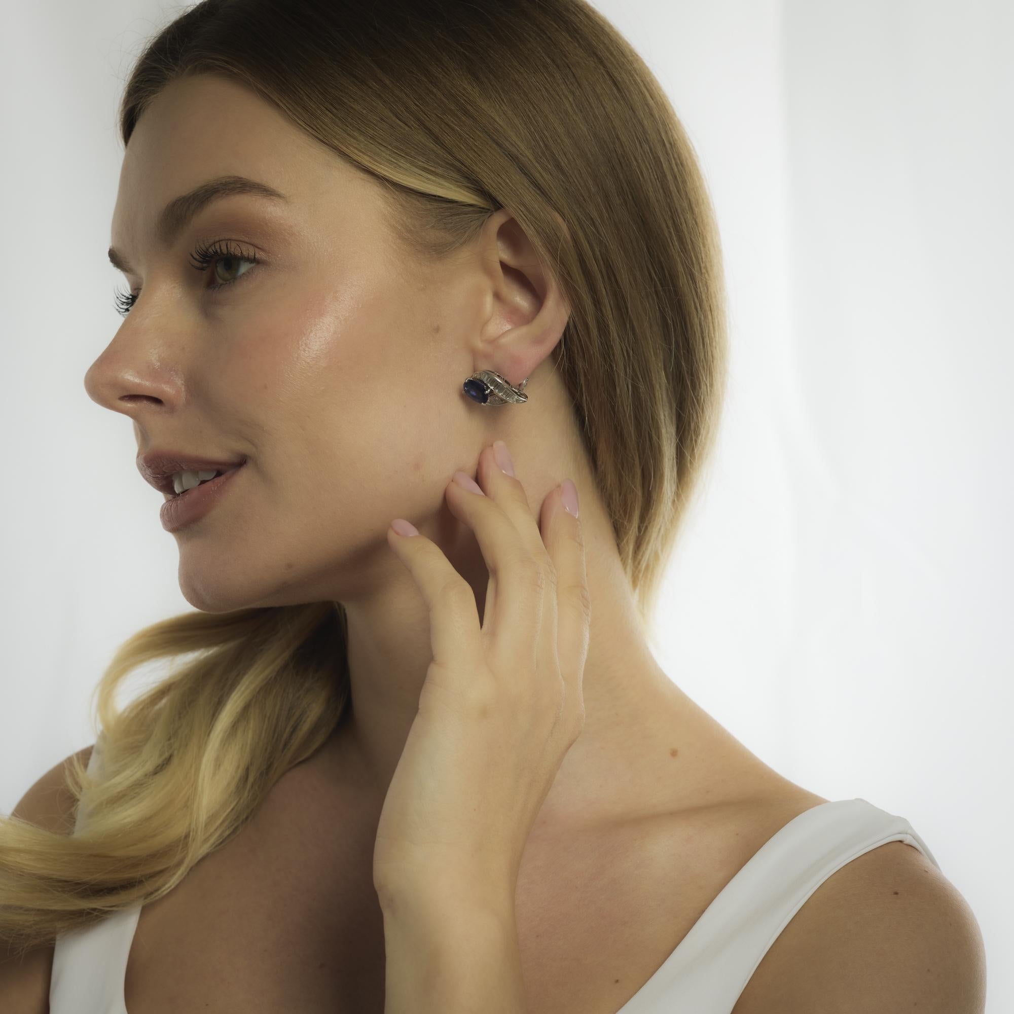 These vintage Oscar Heyman platinum earrings from the 1980’s feature two vivid oval cut tanzanites totaling approximately 5.80 carats. Surrounding each gem, forty-two tapered baguette cut diamonds totaling about 2.00 carats in D-E color and VS