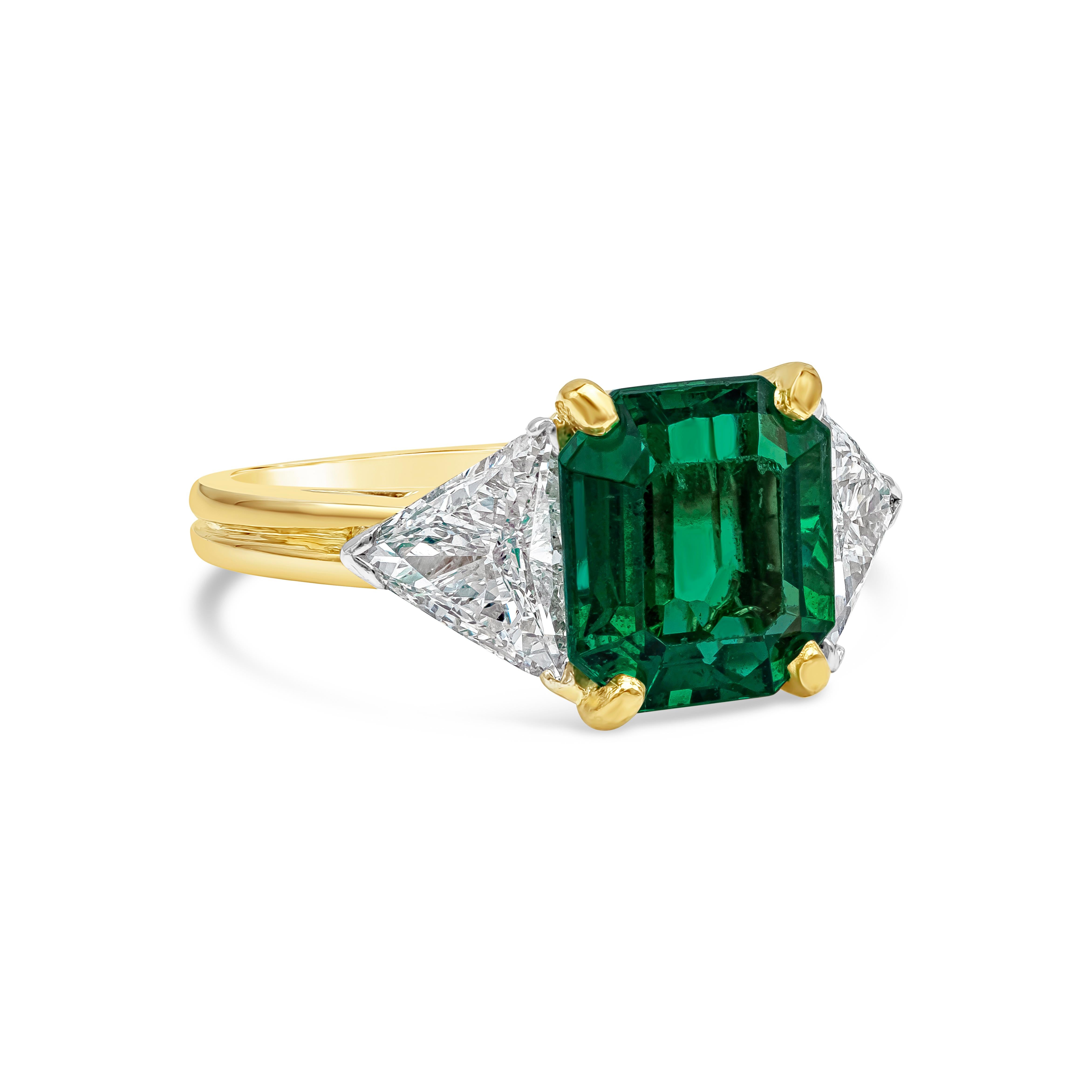 A beautiful gemstone three-stone engagement ring style showcasing 2.91 carat emerald cut green emerald gemstone, VS in Clarity. Flanked by a brilliant trillion cut diamond on each side weighing 1.21 carats total, D-E Color, VS2 in Clarity. Made with
