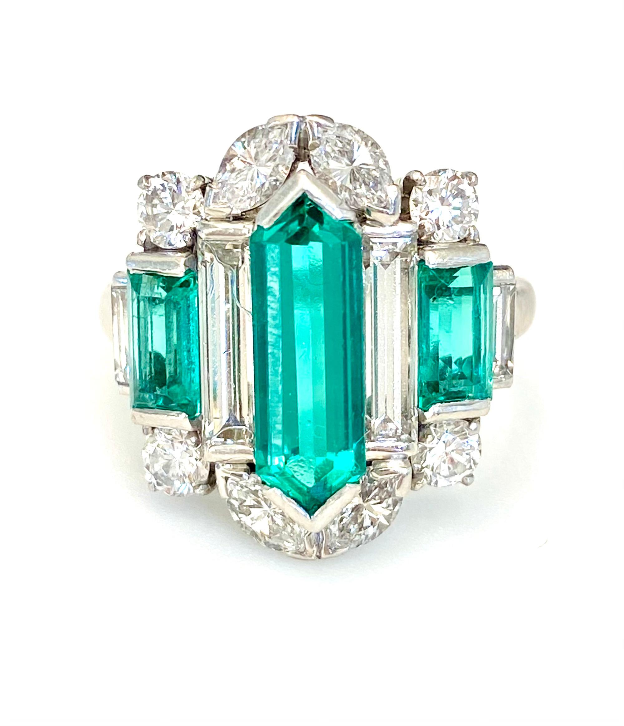 This design consists of a center double bullet cut Colombian emerald flanked by unusual long baguette emeralds, and further accented top and bottom with marquis and European cut diamonds.  Hand made in platinum, the center emerald weighs 2.46 its,