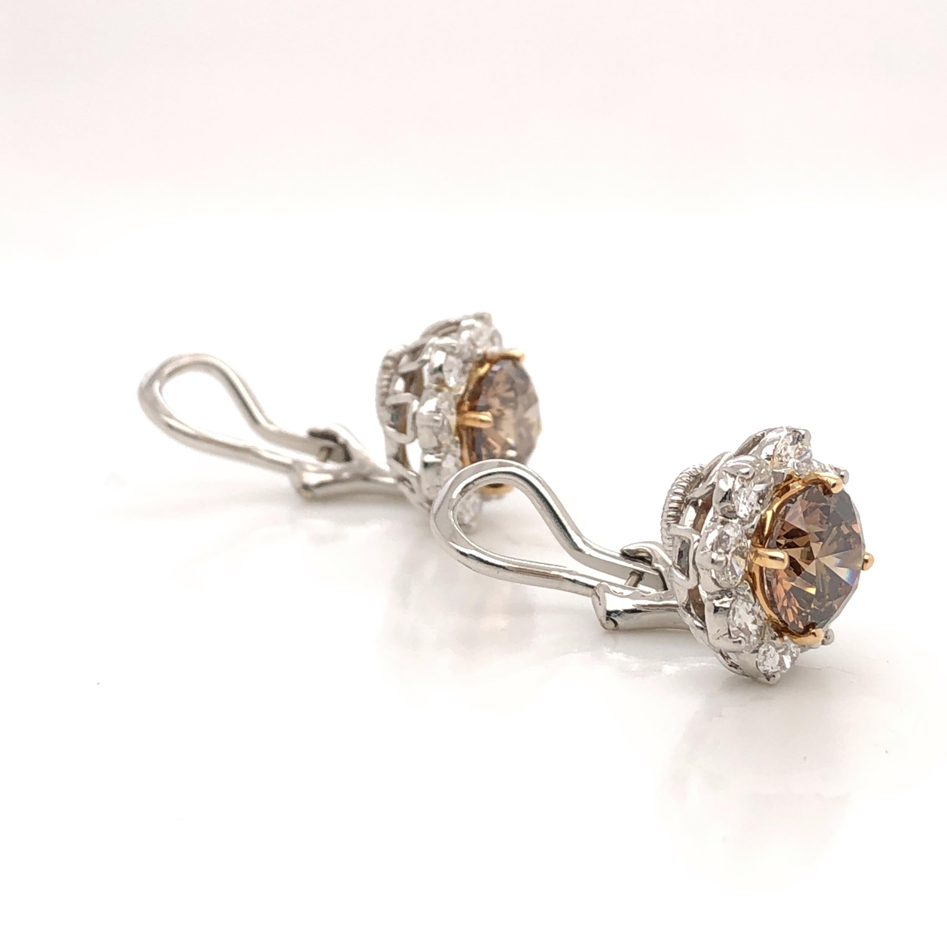 Oscar Heyman platinum and 18 karat gold earrings contain 2 cushion cognac diamonds (3.10cts VS2 & SI1) and 16 oval diamonds (1.08cts F-G/ VS). It is stamped with the makers mark, 18K and IRID PLAT, and serial number 706021.

Earrings measure 12mm H