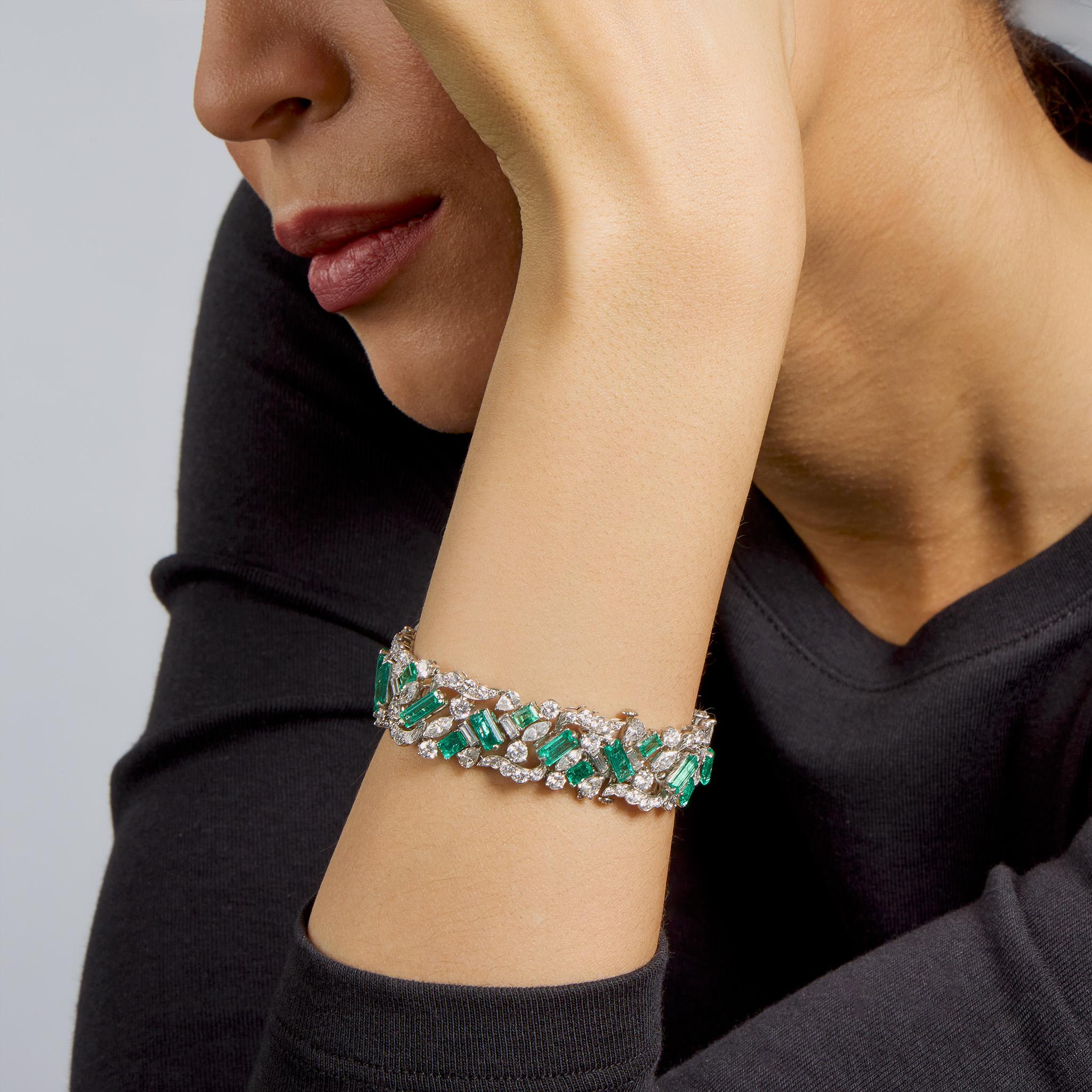 Dating from the 1960s, this emerald and diamond bracelet by Oscar Heyman, New York, is set in platinum. The articulated strap is set with baguette-cut emeralds arranged in a chevron pattern, interspersed with marquise, pear, and round brilliant-cut