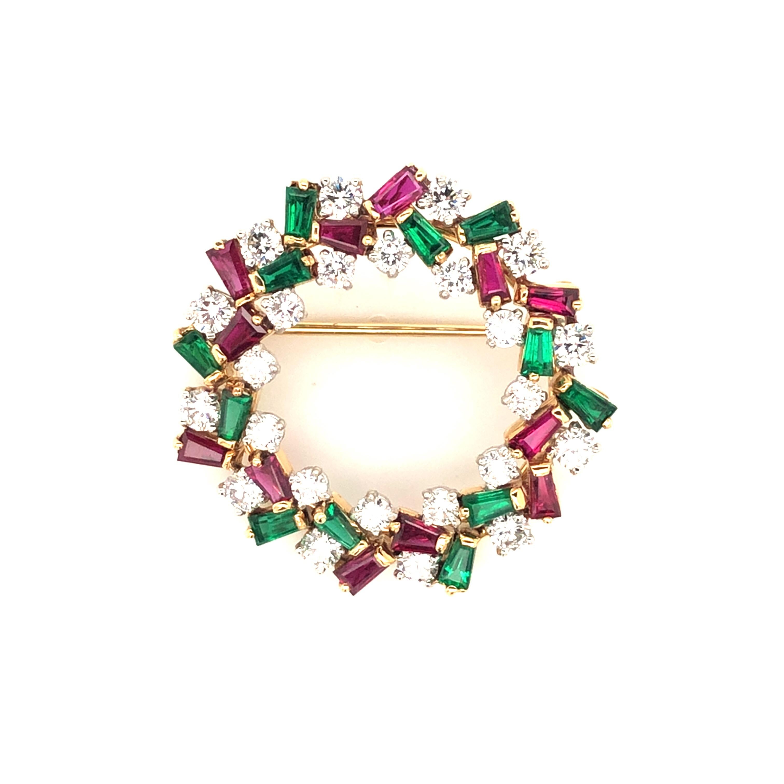 Oscar Heyman 18k yellow gold and platinum holiday wreath brooch contains baguette rubies (2.02cts), baguette emeralds (1.99cts) and round diamonds (2.46cts). The diameter of the brooch is 33mm. It is stamped with the makers mark, 18K and PLAT, and