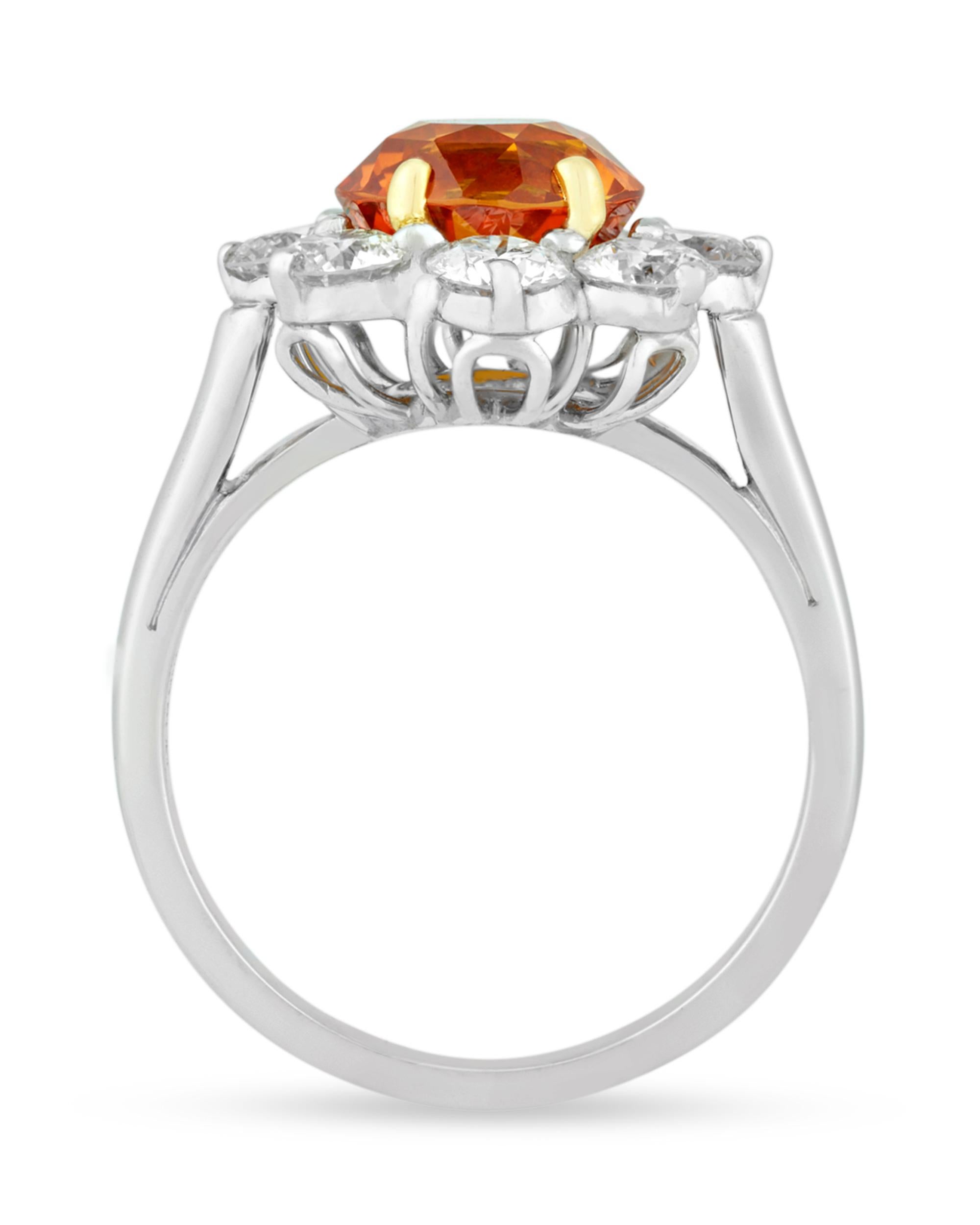 A fiery round, brilliant-cut sapphire weighing 3.13 carats forms the center of this sophisticated ring by beloved American jeweler Oscar Heyman. Certified by the Gemological Institute of America, the jewel displays a vivid orange hue. Encircled by