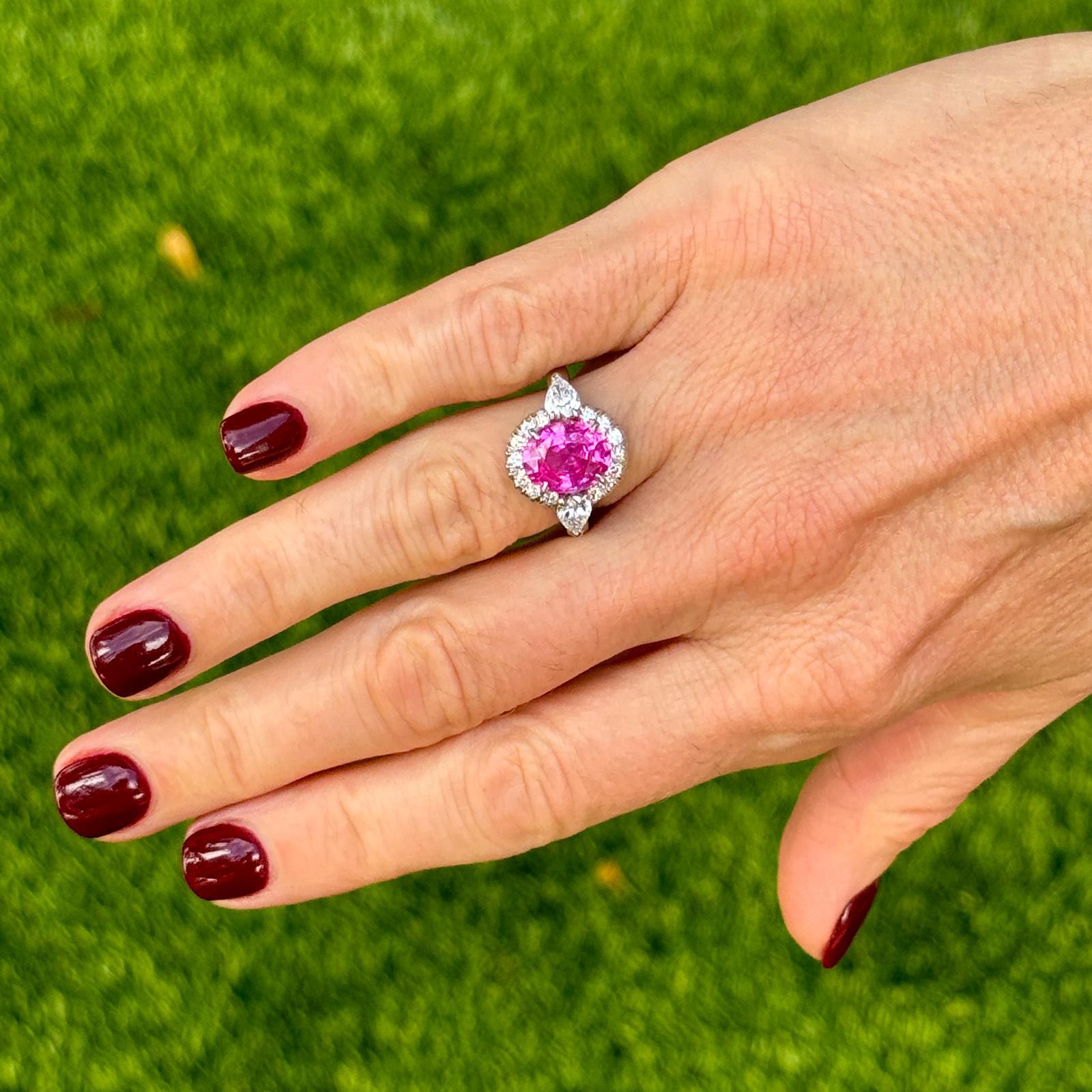 Stunning pink sapphire diamond cocktail ring by Oscar Heyman handcrafted in platinum. The ring features an oval pink sapphire gemstone weighing 3.60 carat flanked by two pear shape diamonds weighing .80 CTW and 14 round brilliant cut diamonds