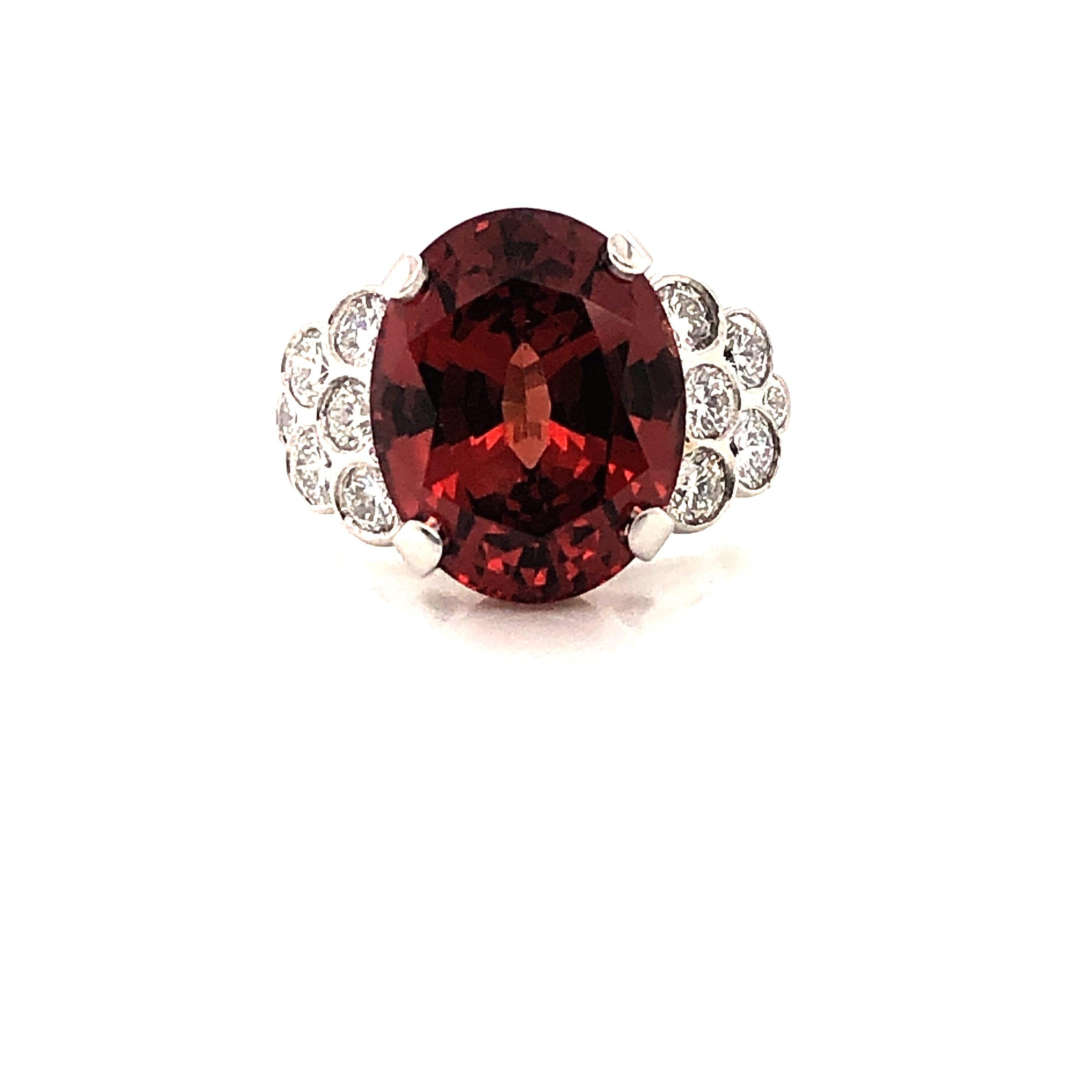 Oscar Heyman platinum ring contains a 10.08ct Malaya Garnet measuring 14.50mm x 11.60mm with a gorgeous deep brownish orange hue and 12 round diamonds (1.12cts, F-G/VS). It is stamped with the makers mark, IRID PLAT, and serial number 302200.

Size