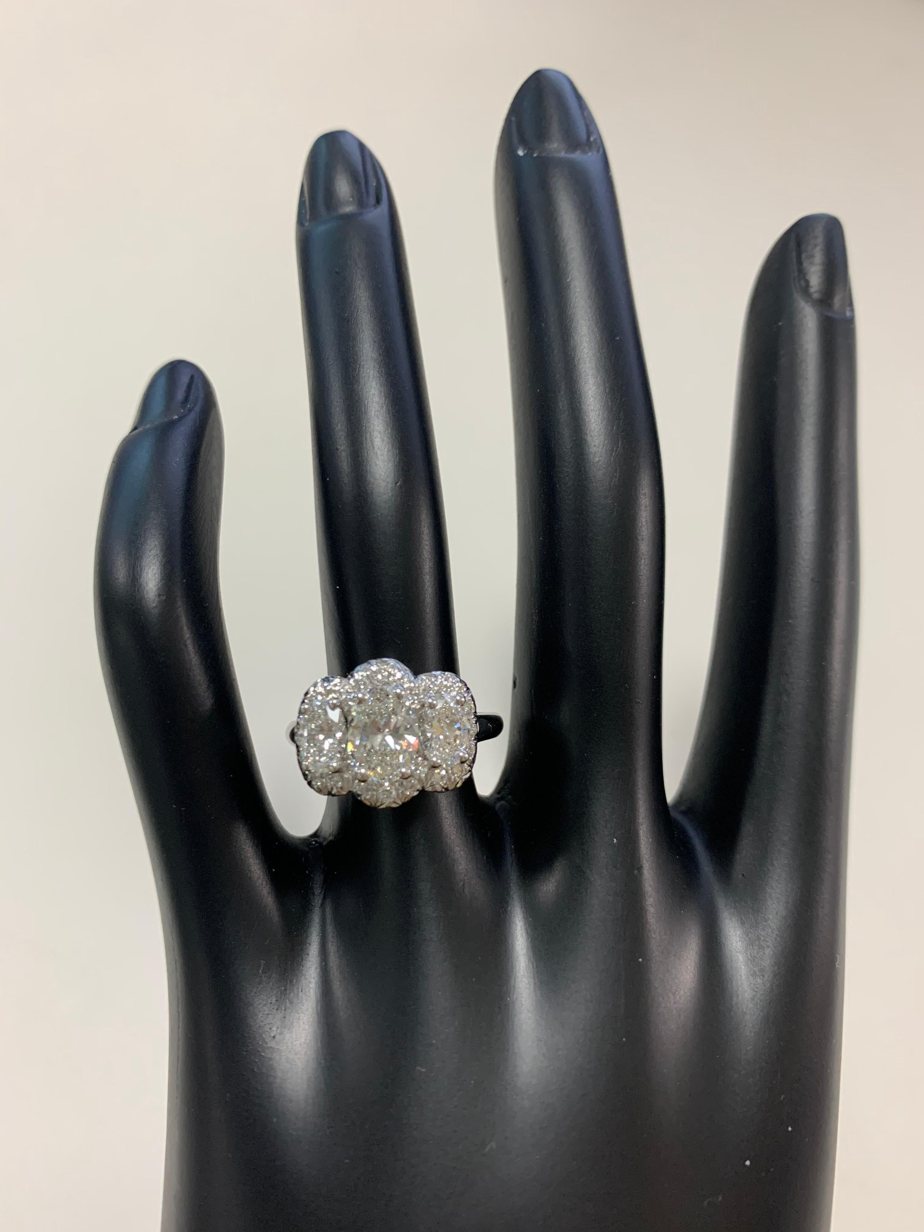 Oscar Heyman platinum oval diamond three stone engagement ring with pave halo contains a 1.20ct center stone (F/VS1) and two side stones 1.02tcw (E/VS1), all with GIA reports.  The pave halo contains 24 round diamonds (0.36tcw). The total width of