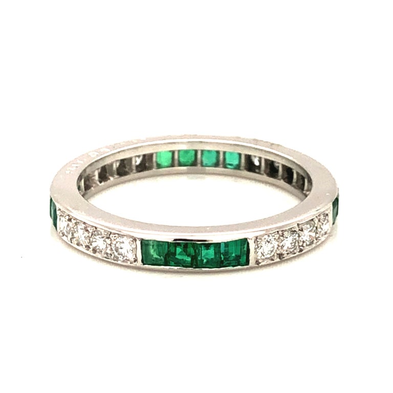 Oscar Heyman platinum wedding band ring contains 16 square emeralds (1.00cts) and 16 round diamonds (0.49cts, F-G/ VS+ quality) that are channel set. It is stamped with the makers mark, IRID PLAT, and serial number W4367.

Size 9.5. Cannot be