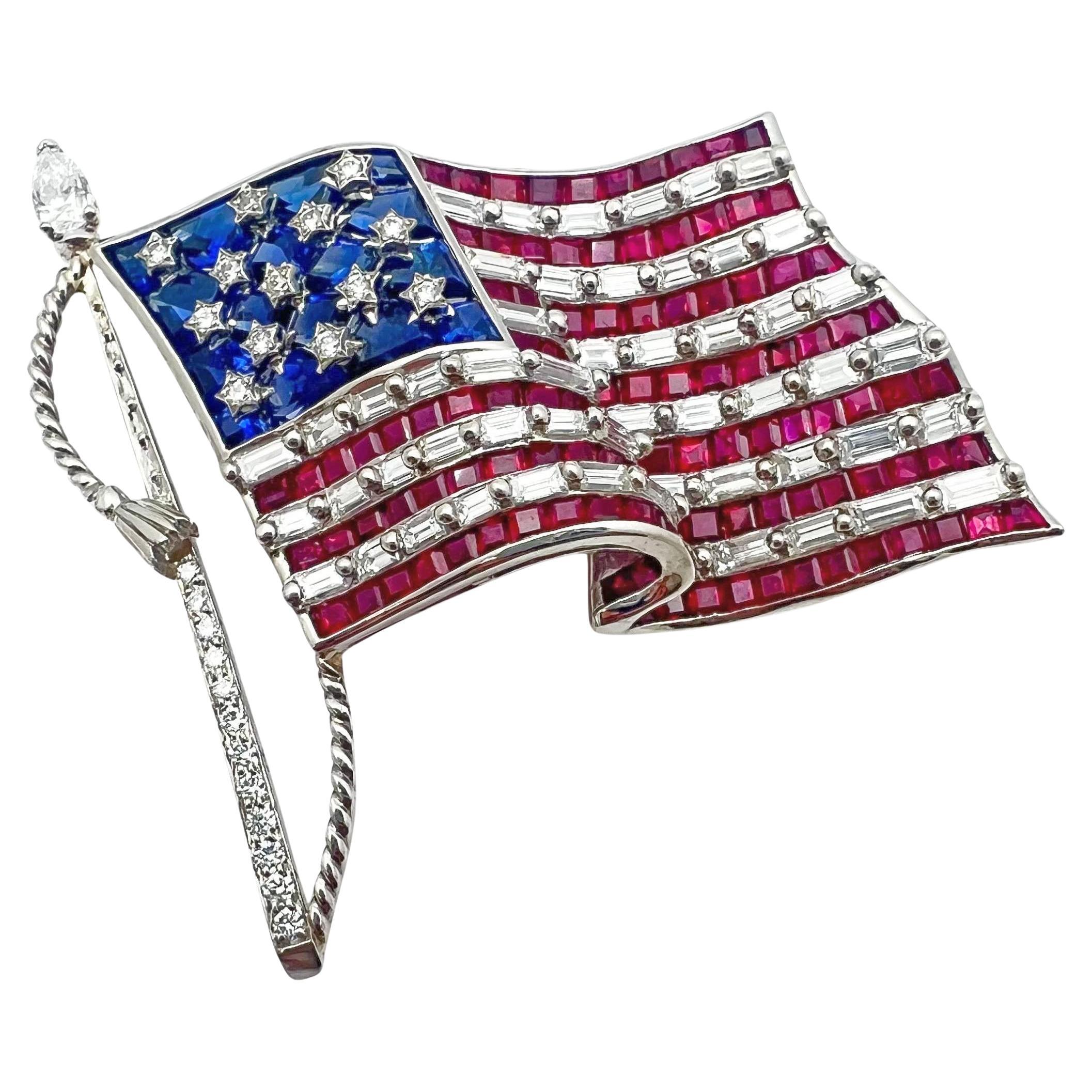 Large size Oscar Heyman American flag pin in platinum, featuring baguette-cut ruby and diamond-set stripes, embellished by mixed-cut blue sapphires with brilliant-cut diamond stars, the flag flying from a brilliant-cut diamond-set pole with a