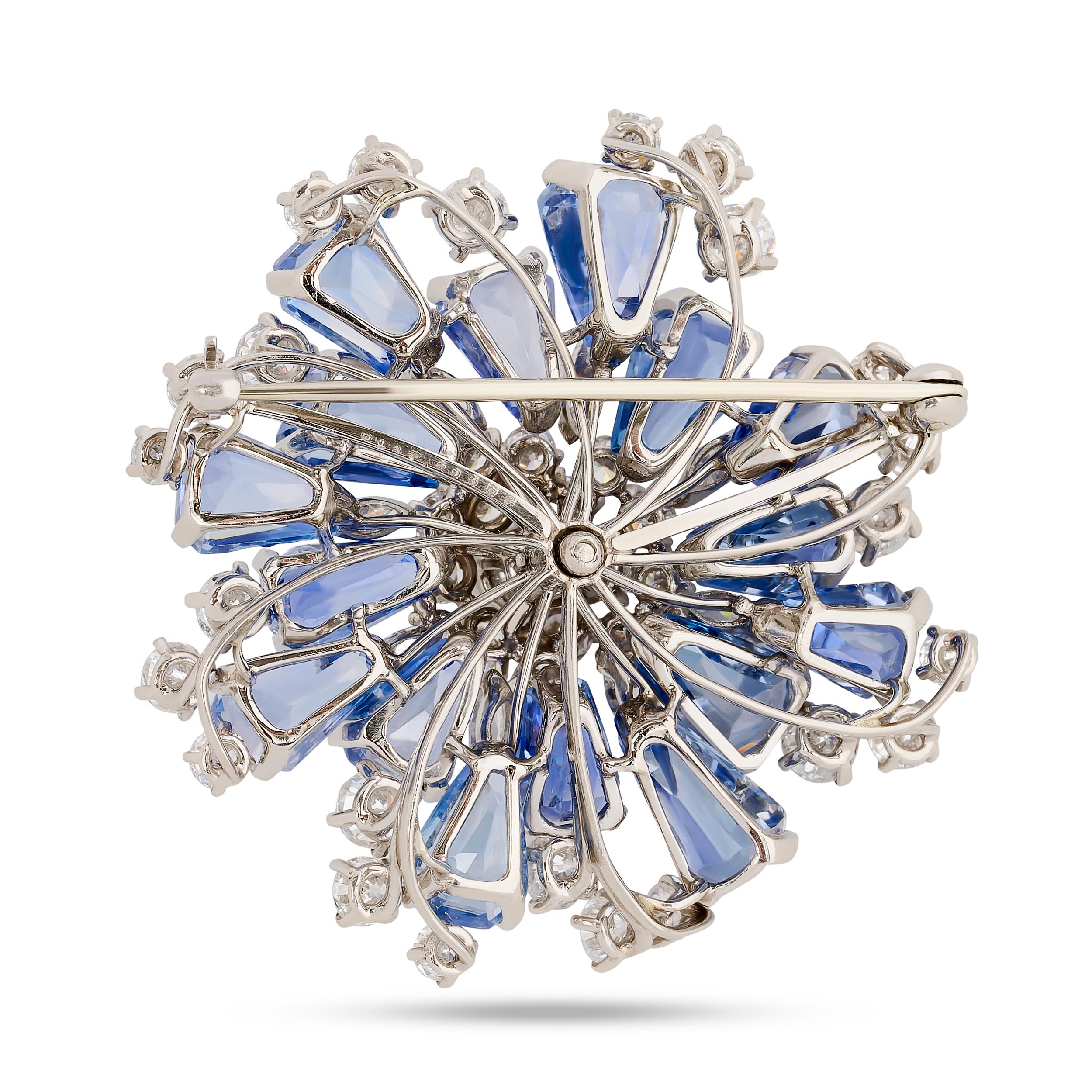 Cette magnifique épinglette en saphir et diamant d'Oscar Heyman présente un motif en forme de flocon de neige, avec des saphirs bleus rayonnants de taille trapézoïdale et marquise entourés de diamants de taille brillant, le tout centré sur un gros