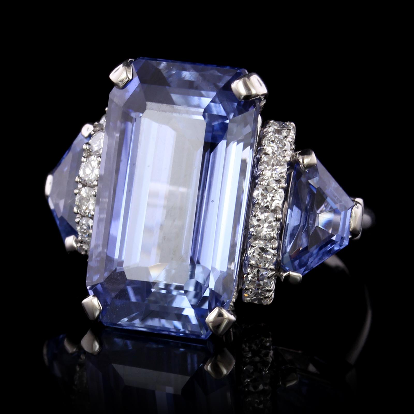 Oscar Heyman Platinum Sapphire and Diamond Ring. The ring is set with one
emerald cut sapphire weighing 19.52cts., AGL #1084837, no heat, origin Ceylon, and
two sheild cut sapphires weighing 1.28cts., and 1.38cts., AGL #108662 A & B, no heat, origin