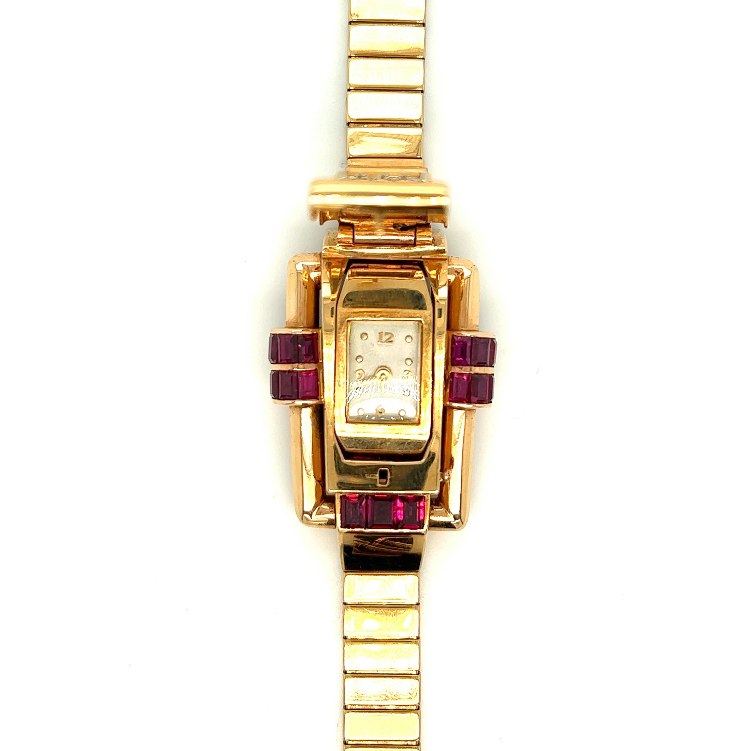 Oscar Heyman retro ruby and diamond watch

Concealed flip dial of mechanical movement, rectangular dial with gold Arabic numbers, and dot markers; calibré-cut rubies and round brilliant-cut diamonds of approximately 0.35 carat; 18 karat rose gold