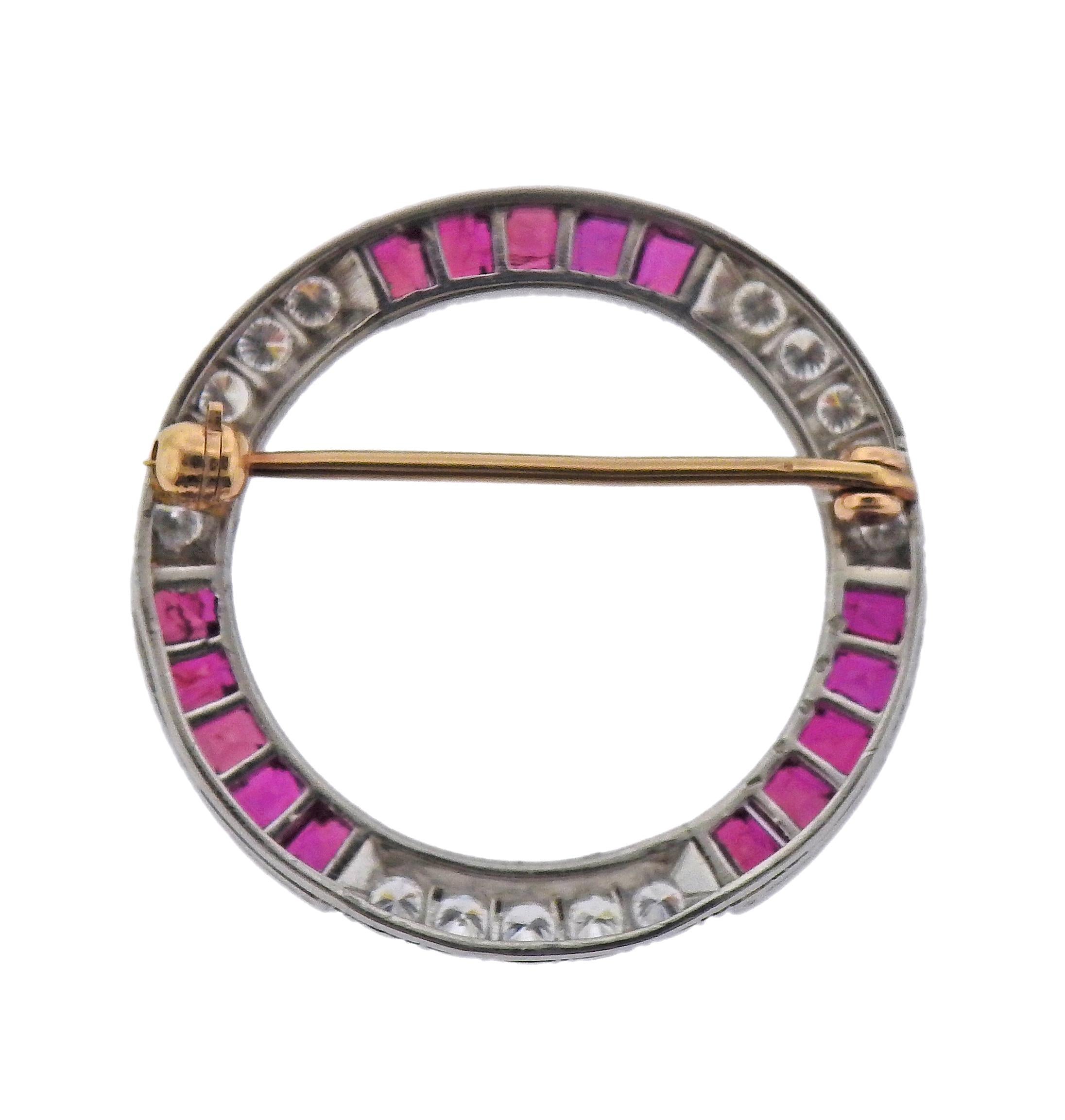 Oscar Heyman circle brooch in platinum with 18k gold hardware. Adorned with square cut rubies and approx. 0.60ctw in diamonds. Brooch is 1 1/16