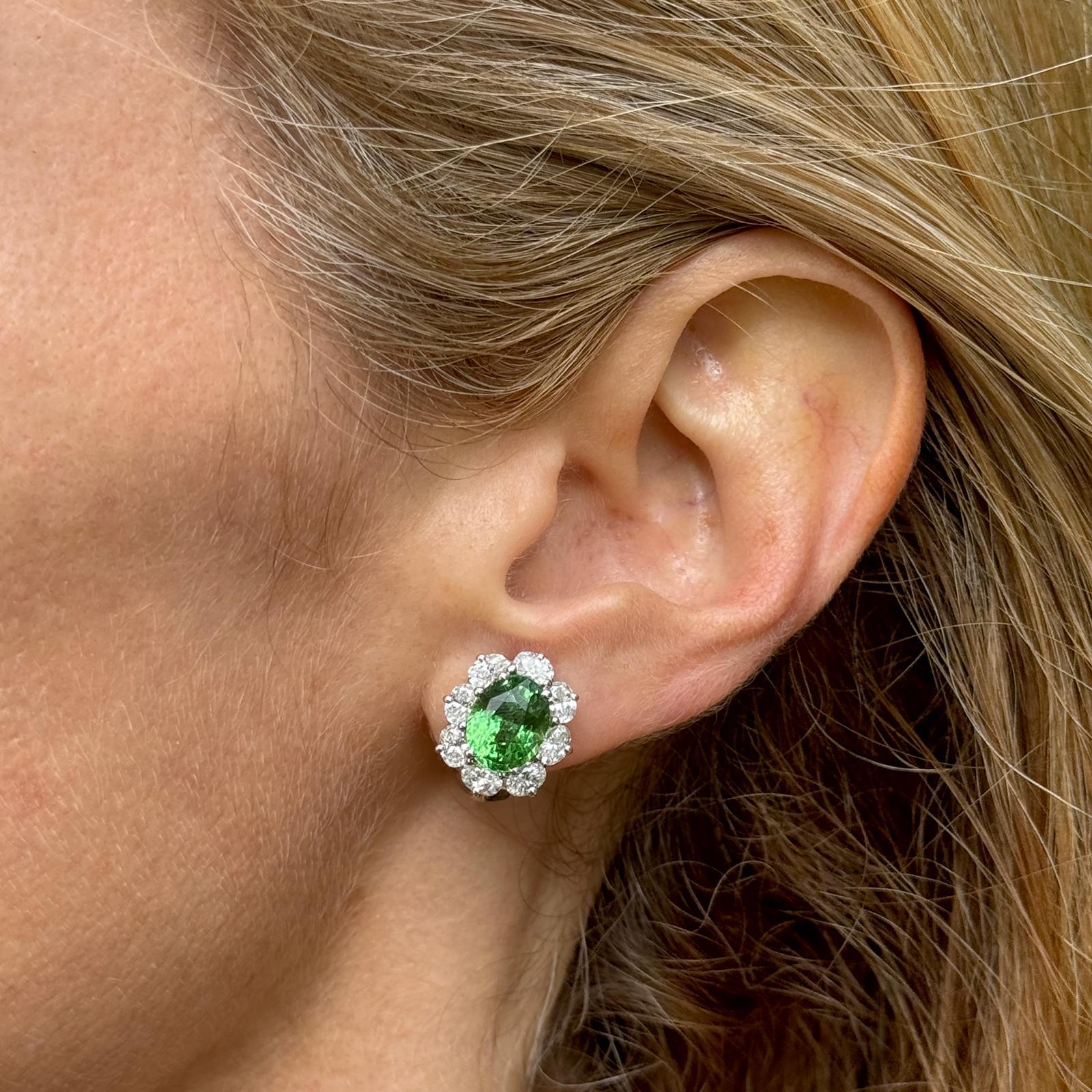 Stunning tsavorite and diamond earrings by American designer Oscar Heyman handcrafted in platinum. The earrings features 2 oval tsavorite gemstones weighing 6.15 carat total weight, and 16 oval cut diamonds weighing 2.18 CTW. The diamonds are graded