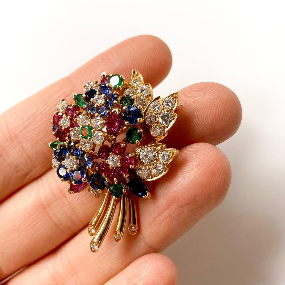 Diseñado como un ramo de flores de zafiro, rubí y diamantes, con pistilos y hojas de esmeralda, engastado en oro amarillo de 18 quilates. 

Con el sello 