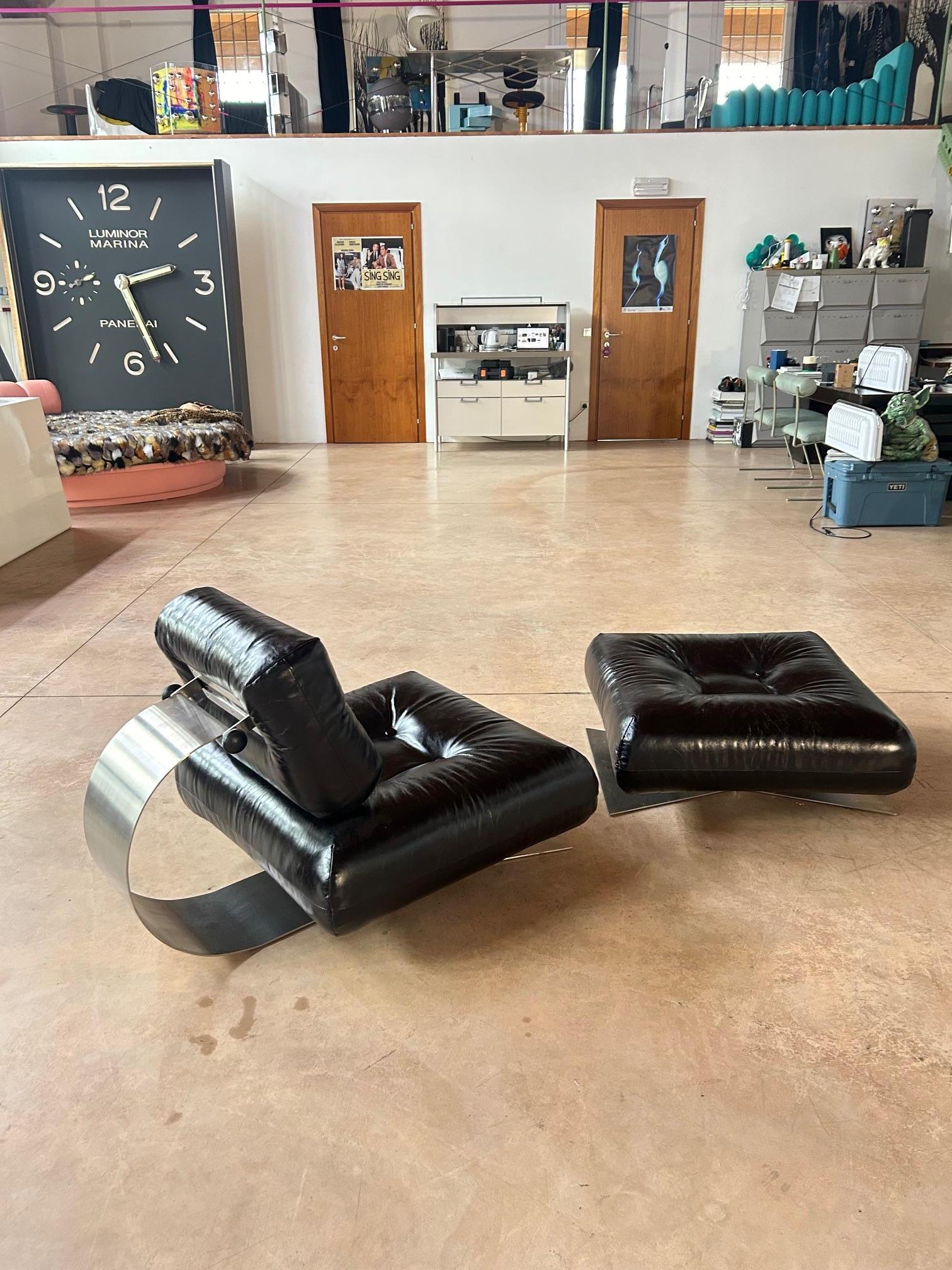 Chaise et ottoman Alta de Oascar Niemeyer en cuir noir pour Mobilier International, France. Édition à siège bas. Structure en acier inoxydable satiné, boutons de fixation, dossier réglable. 
Les formes de ce fauteuil reflètent la recherche de la