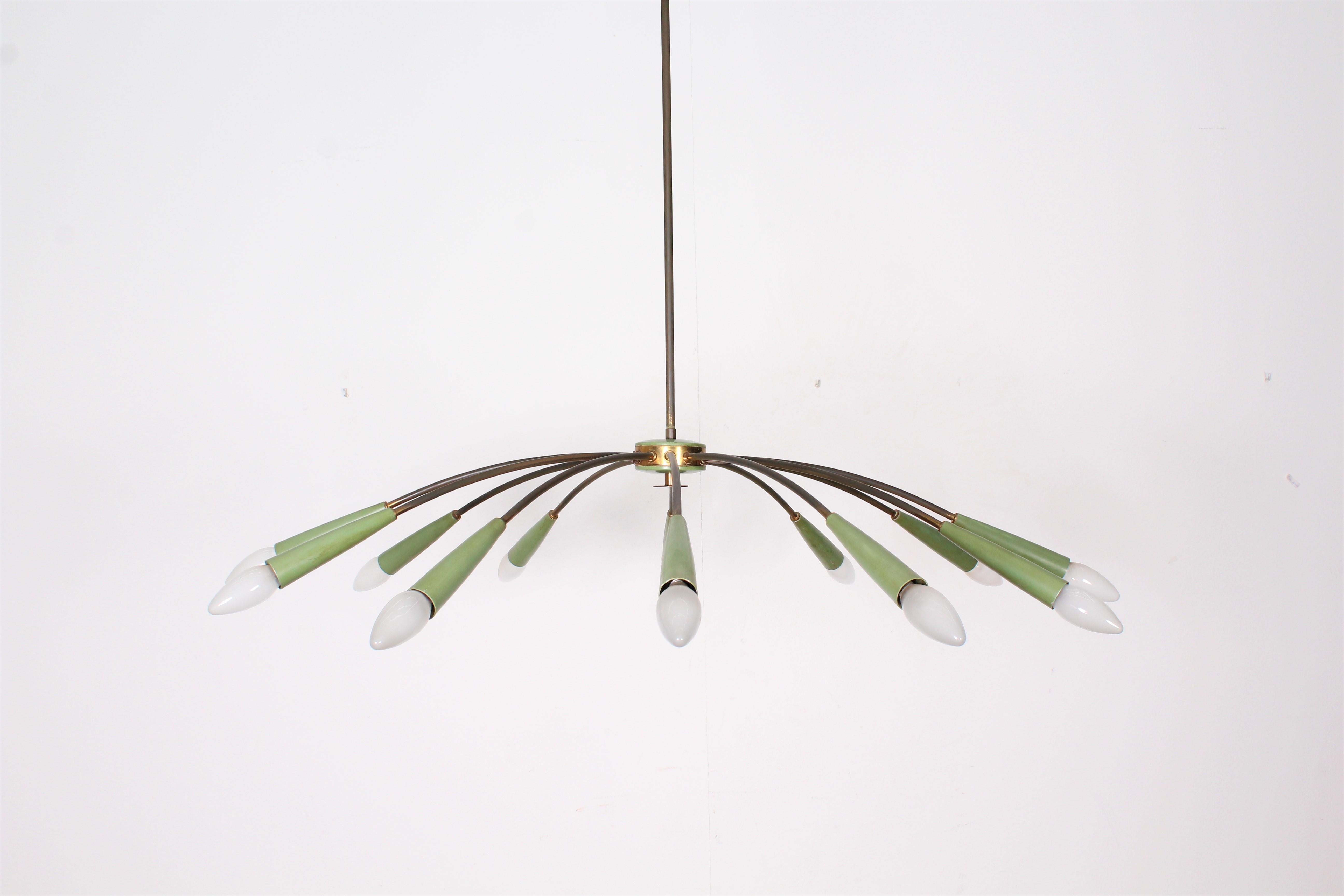  A sculptural 1960s brass Italian sputnik in green metal, designed by Oscar Torlasco for Lumi whit  twelve-light source.
It has 12 graceful arms each curving at theexternal.
Its 95cm diameter provides a broad sphere of light.  
 Wear consistent with