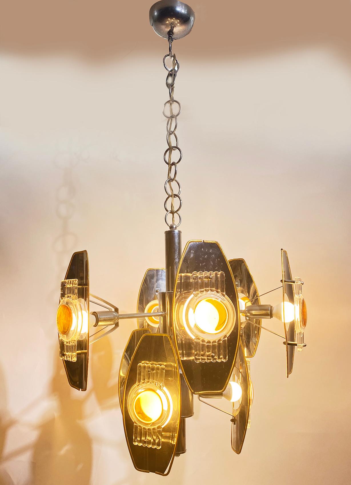 Super stylish and rare metallic chandelier by Oscar Torlasco, Italy 1960. 
The nine chrome arms contain aluminum lamp shades with a gold finish rim which hold 9 large lenses of glass
Having nine bulbs in total. Delivered and wired for American or