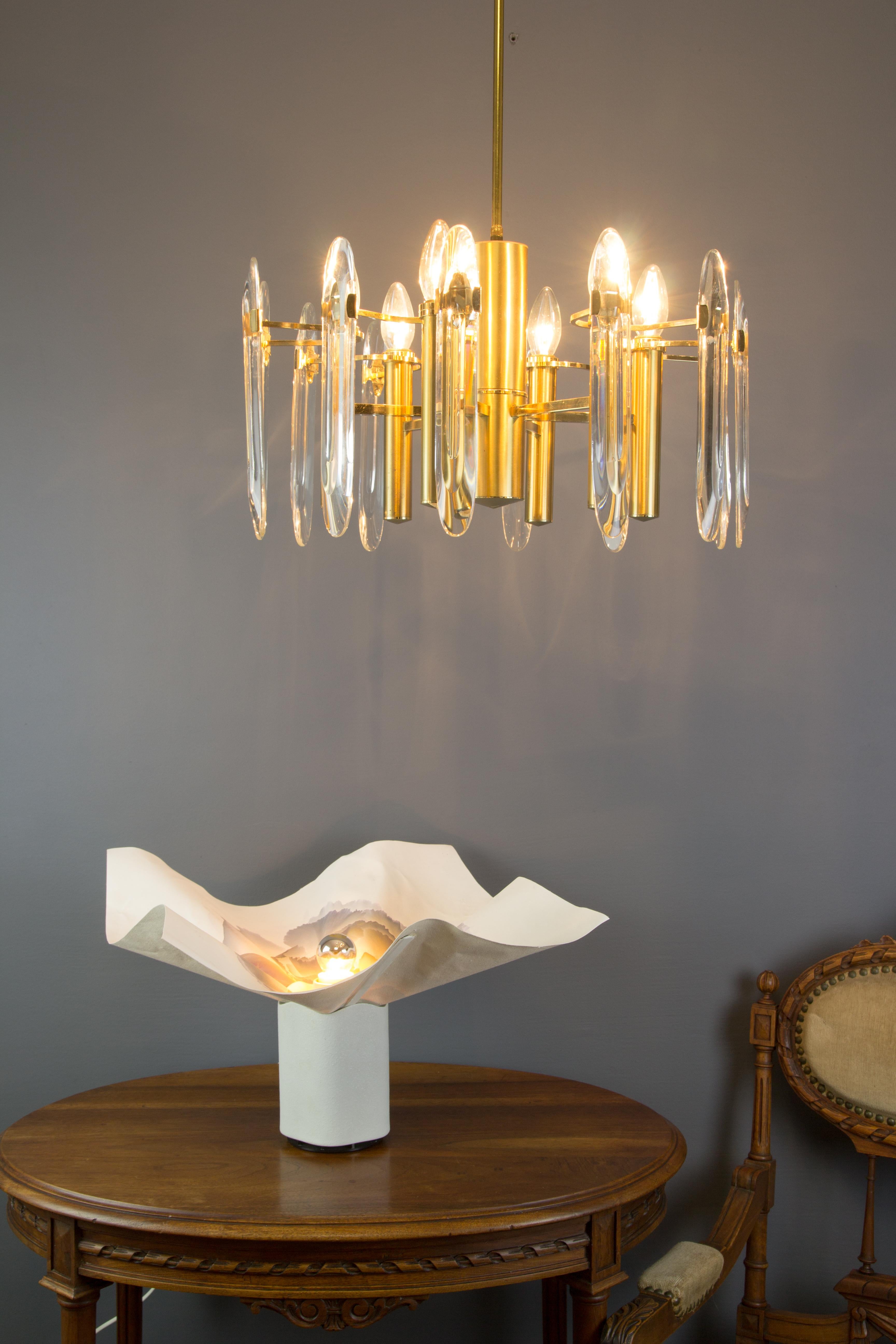 This beautiful chandelier was designed by Oscar Torlasco for Stilkronen in the 1960s, in Italy. The chandelier consists of six arms that correspond to 6-light points which hold 2 glasses/ lenses each for a total of 12 glasses. Golden brass