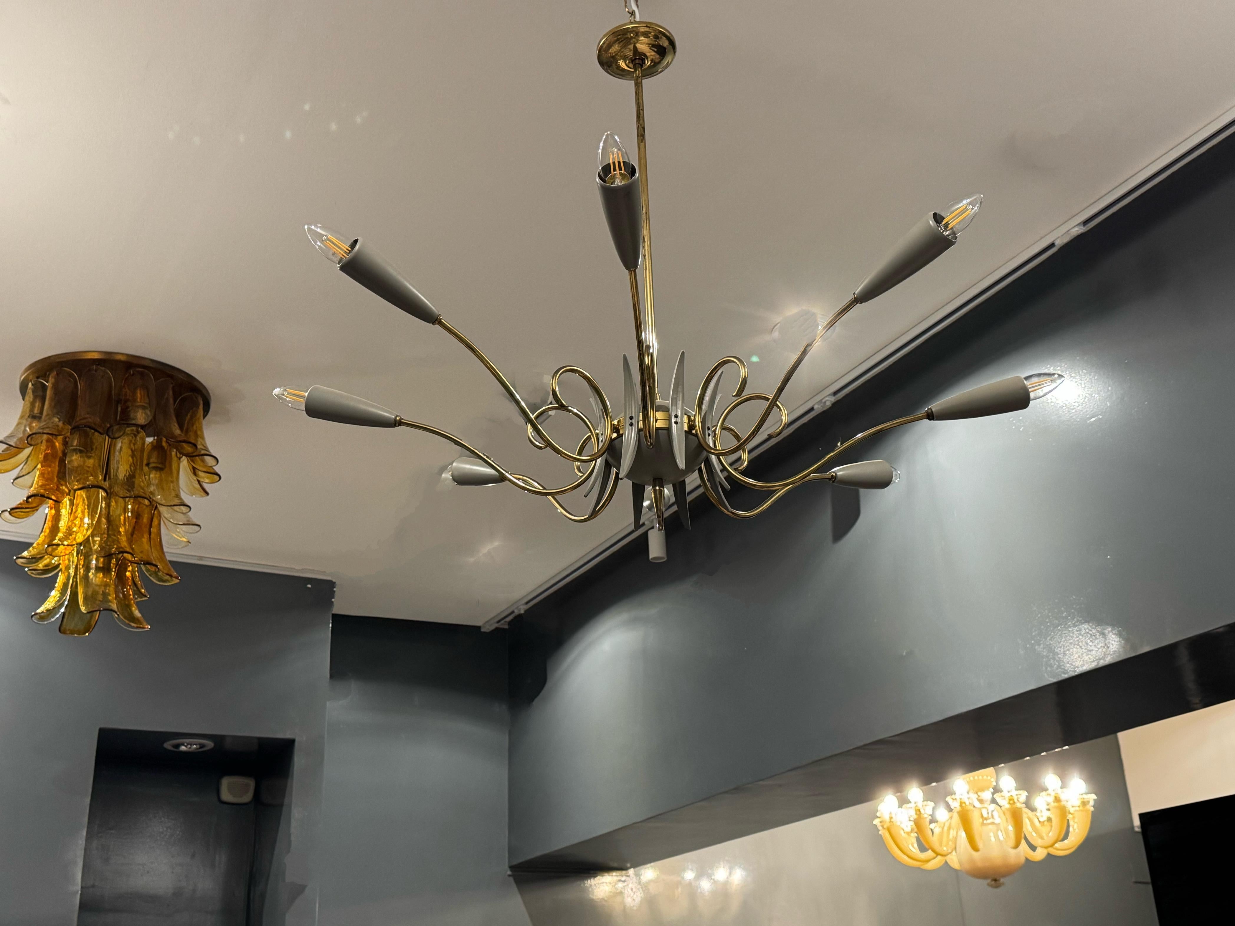 Questo lampadario di Oscar Torlasco, risalente alla metà del secolo scorso e risalente agli anni '50-'60, è un esempio della maestria italiana nel design dell'illuminazione modernista. Realizzato in ottone e metallo laccato, il pezzo presenta una