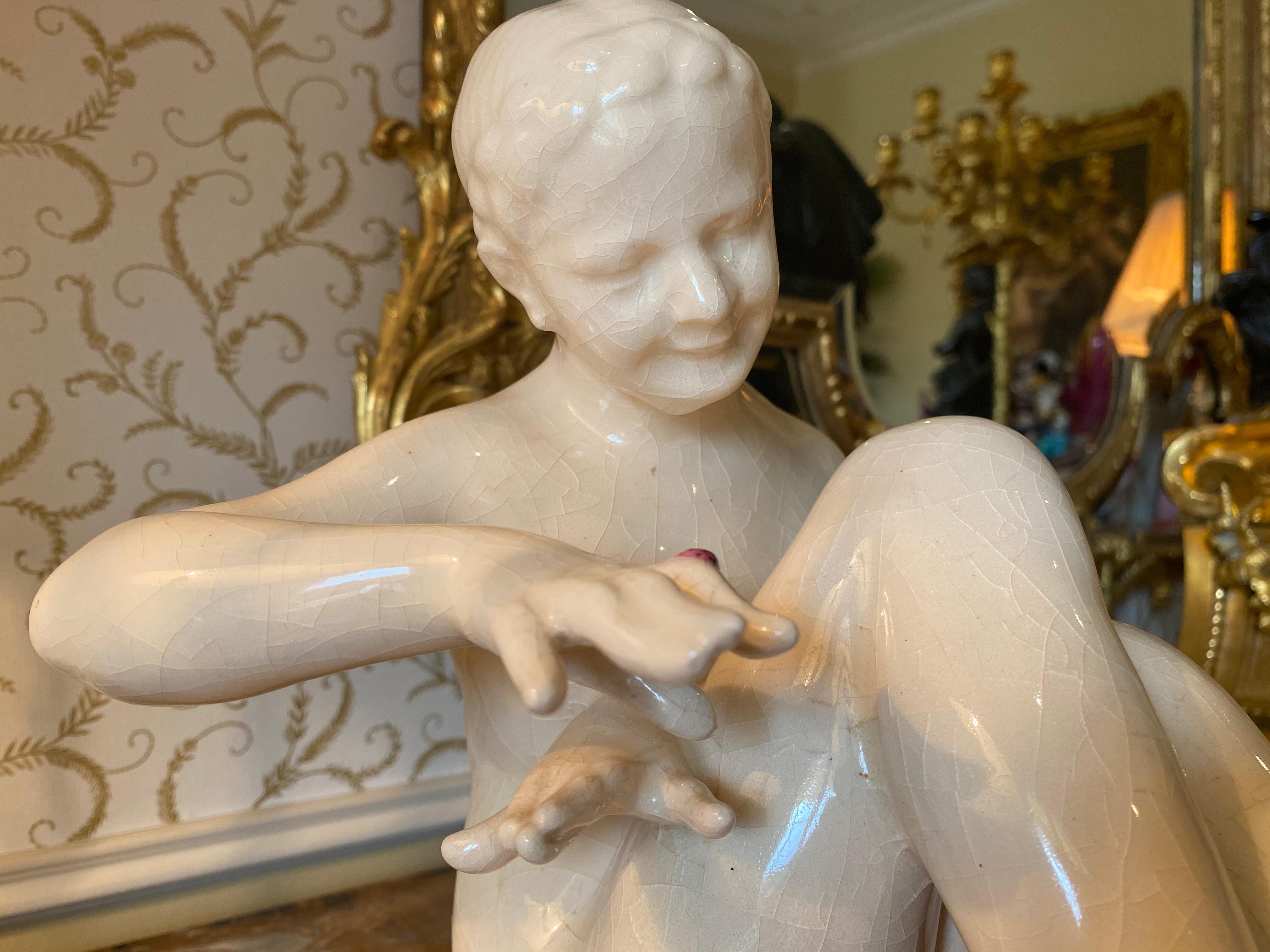 Lovely polychrome enamelled ceramic heightened with gold representing a young woman seated looking on her finger at a small ladybug. Signed on the base 