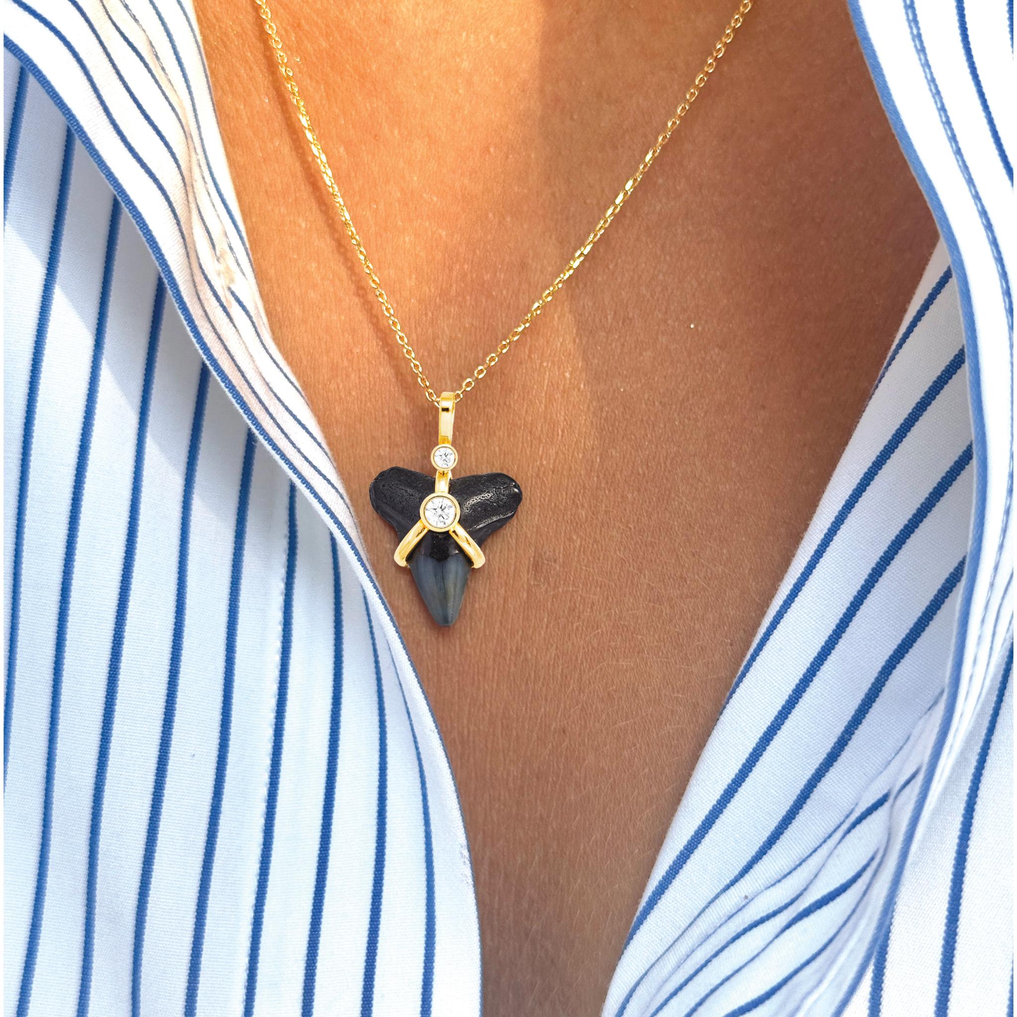La collana Oscuro Shark Tooth è realizzata in vero dente di squalo fossile con oro massiccio 14k e diamanti naturali. Ispirandoci al concetto di surrealismo, abbiamo combinato un oggetto apparentemente ordinario con materiali straordinari, creando