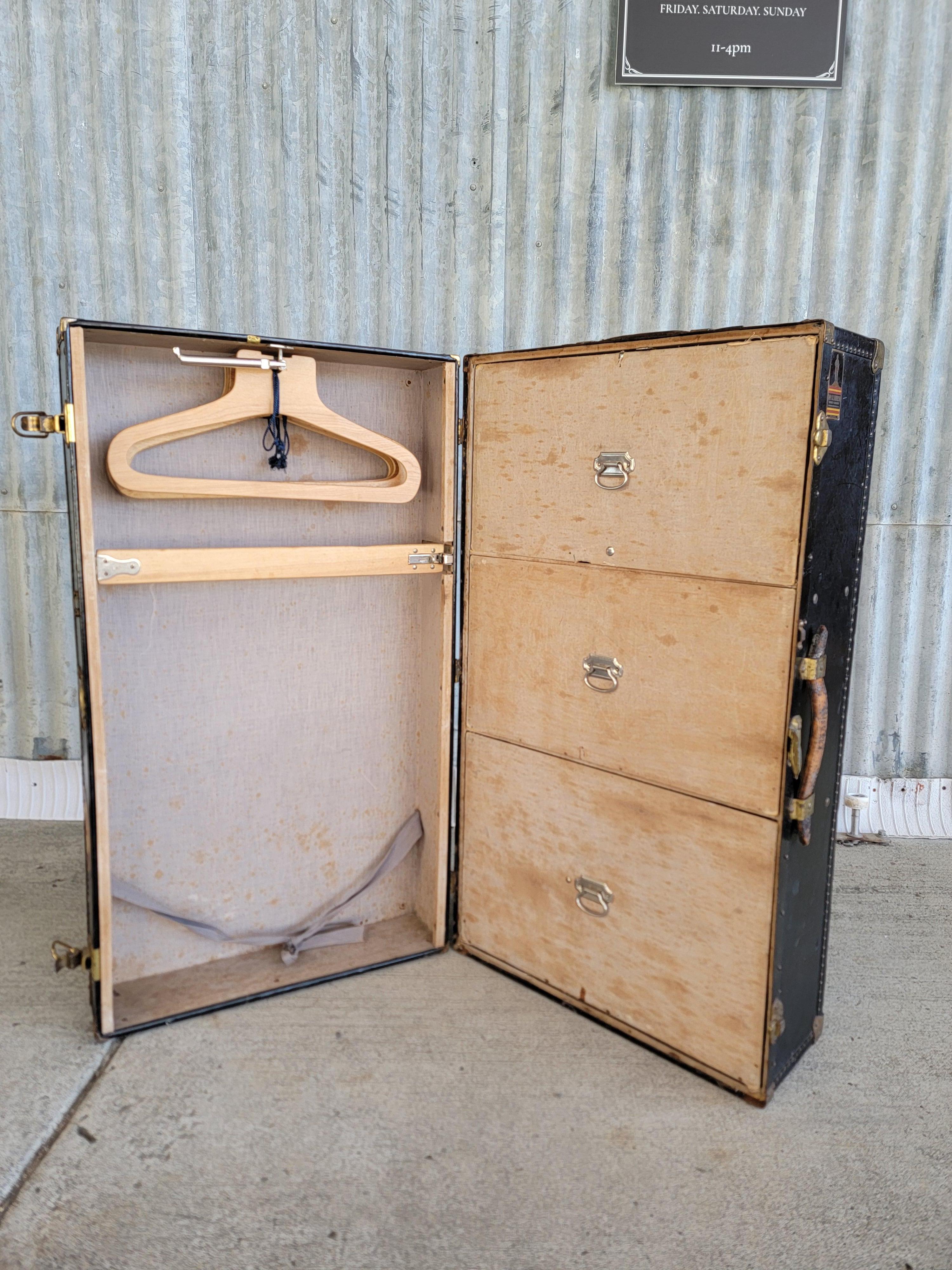 Une malle à vapeur vintage de Oshkosh Trunks & Luggage Inc. Équipée de 3 compartiments de rangement amovibles et d'une section pour suspendre les vêtements, y compris 4 cintres en bois d'origine. Plusieurs labels de voyage sont intacts, notamment