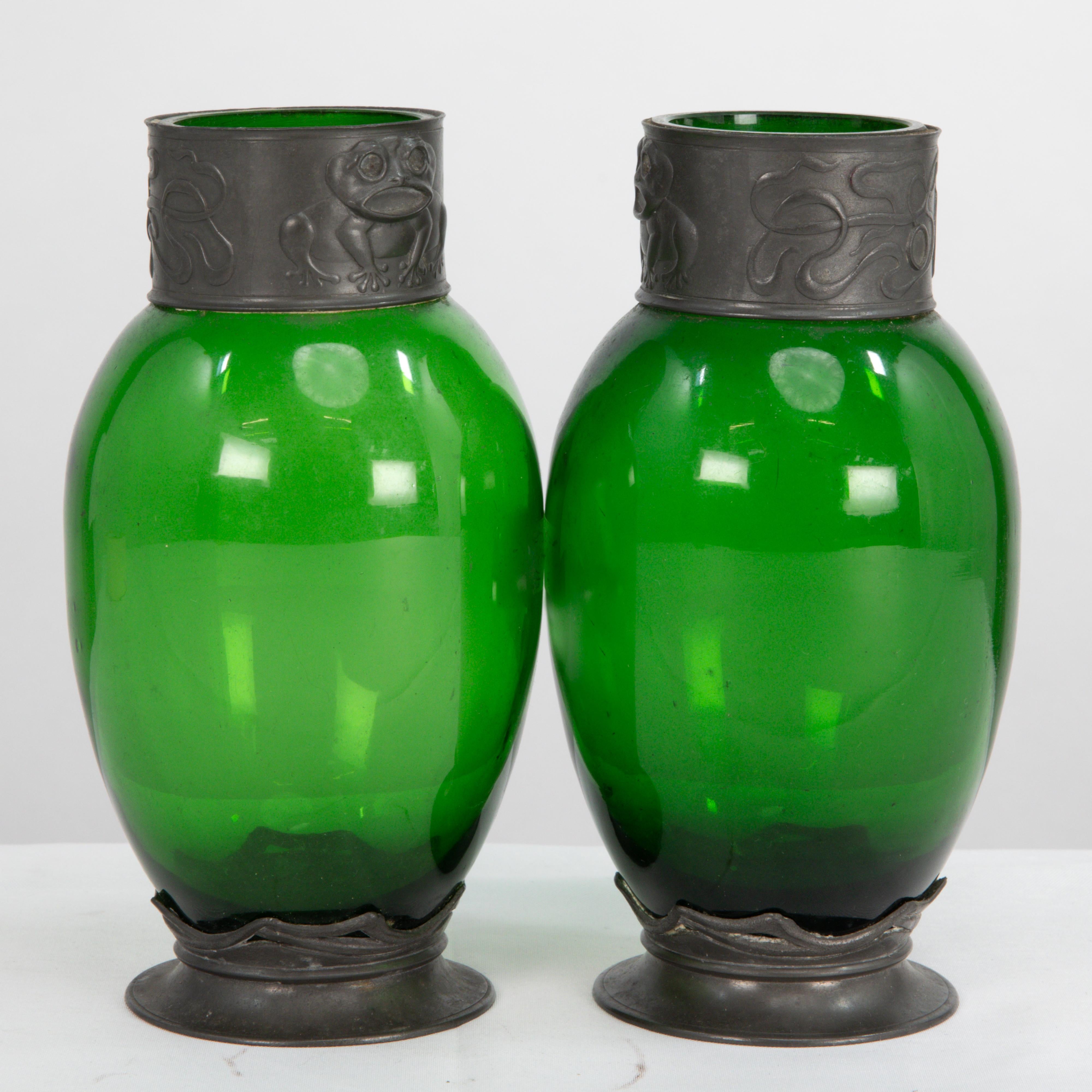 Osiris Pewter. A pair of Art Nouveau pewter and green glass vases decorated with little frogs to the rims.