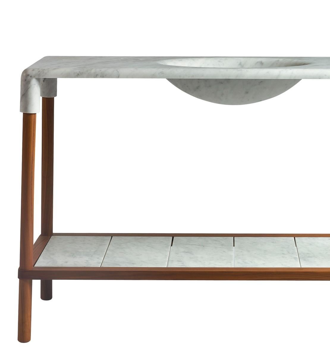 Designed by Gritti Rollo, this elegant console is part of the Oslo collection, an elegant series of pieces of midcentury inspiration that boast a top in marble bending at the corners to enclose the structure in walnut. The standout element of this
