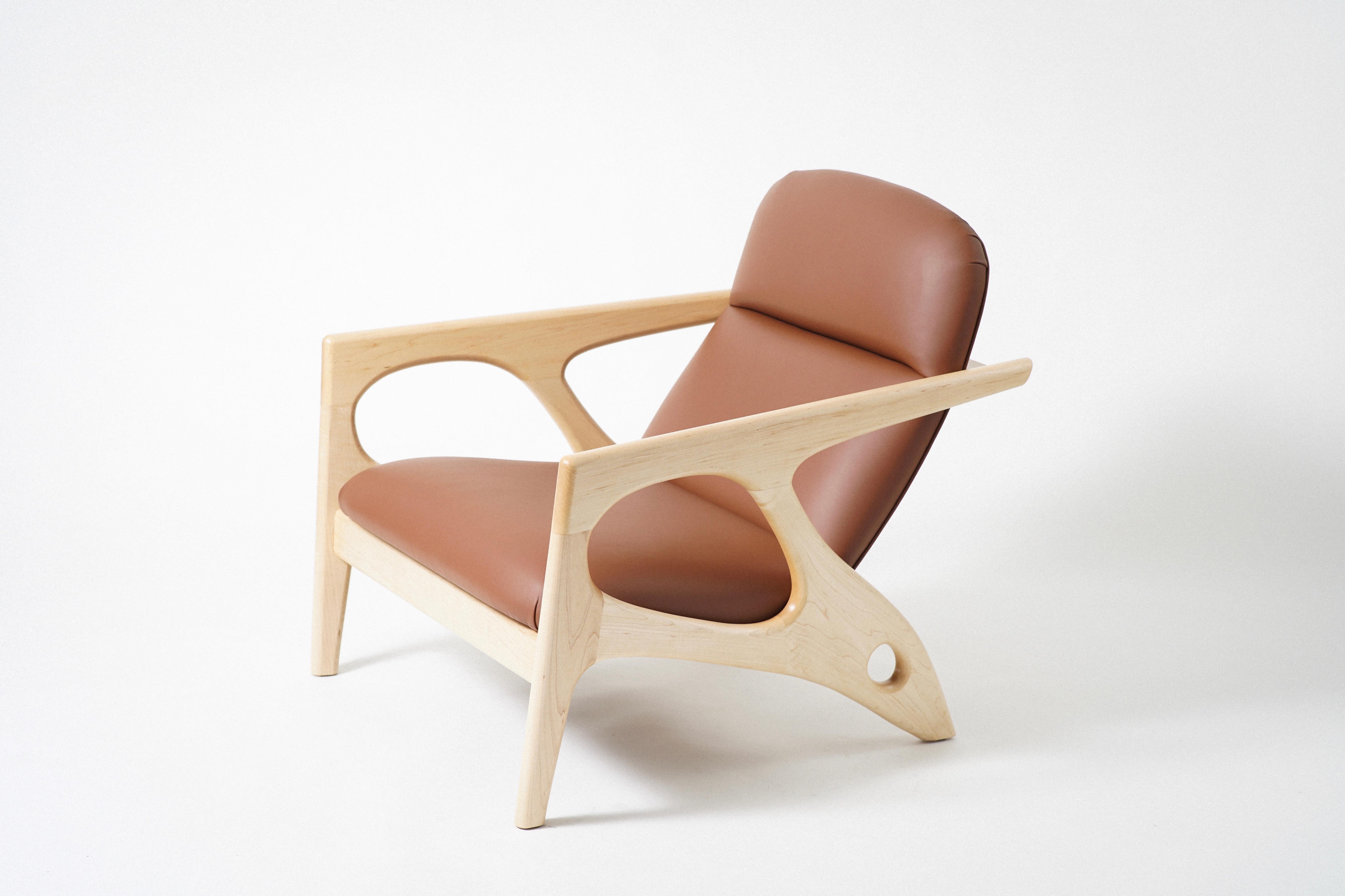 The Osprey Lounge Chair has an exposed hardwood frame that cradles an upholstered shell, with leather upholstery. The unique frame takes inspiration from both nautical design and the natural world. The generous frame opens up and tapers back, like a