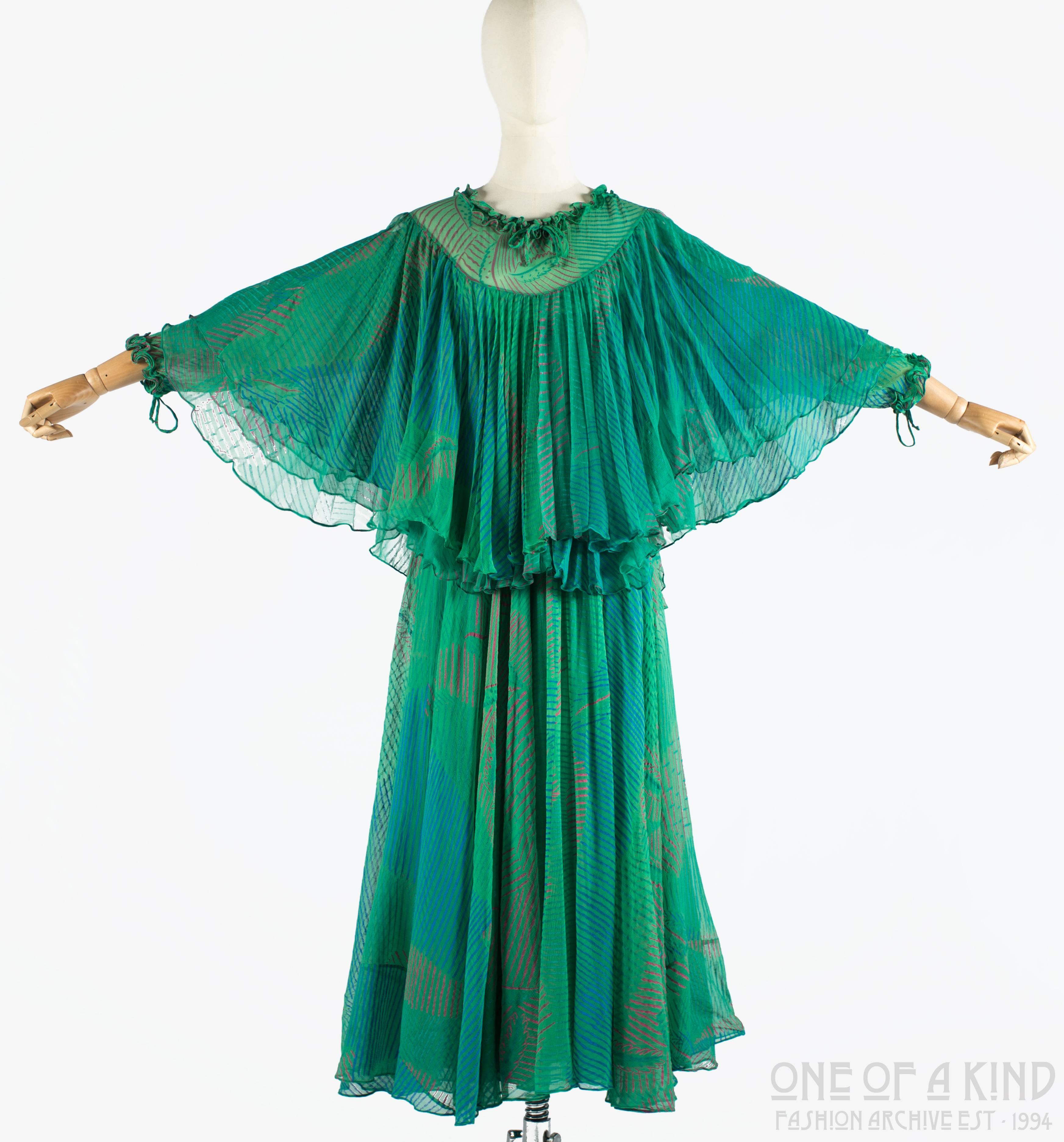 Ossie Clark green silk evening dress with print by Celia Birtwell 

- Drawstring fastenings at neck and cuffs with ruffled trim
- Semi-sheer yoke
- Two pleated panels around the bust 
- Full skirt with silk lining
-  during the mid to late 70s