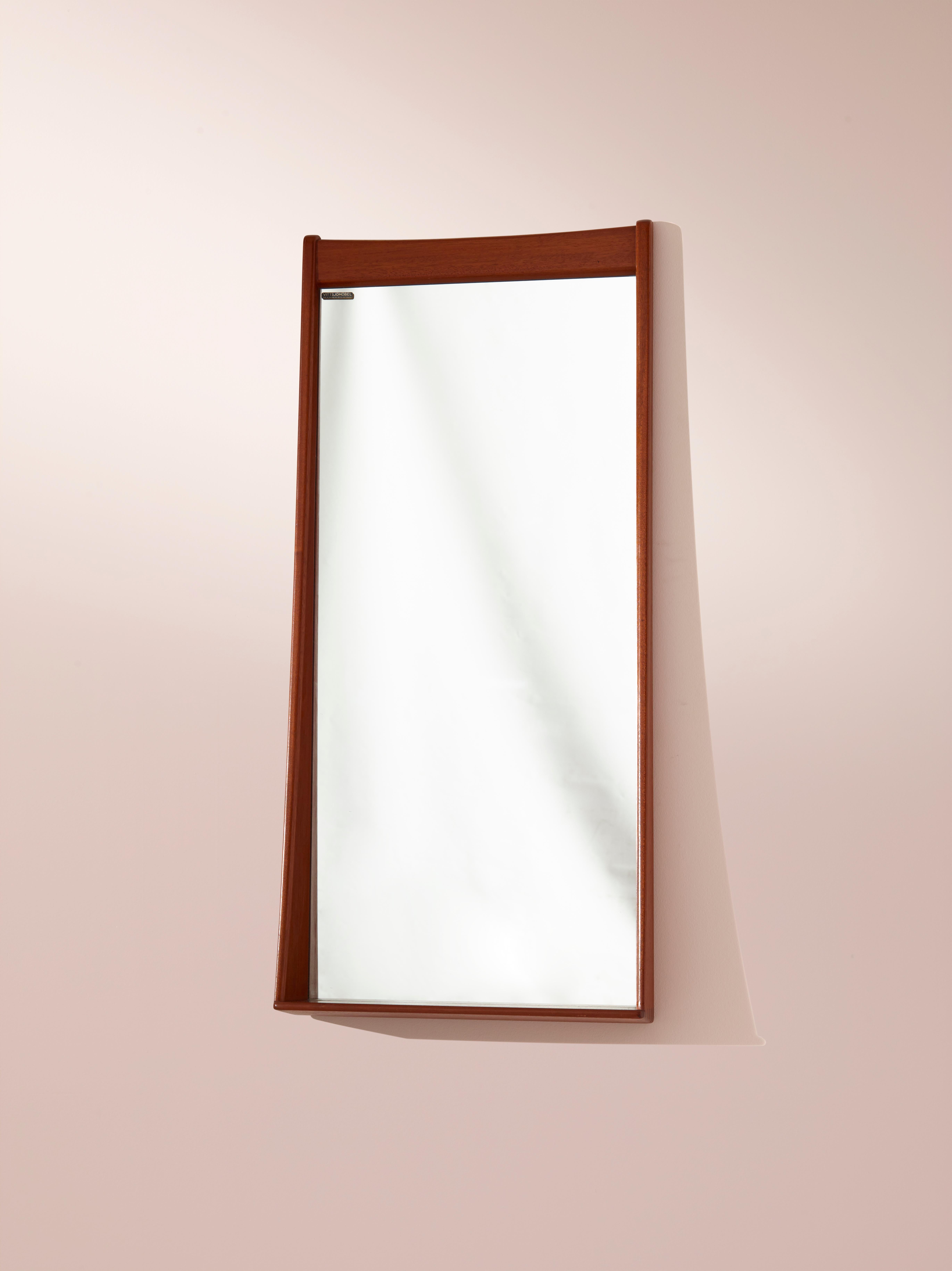 This 1950s Swedish wall mirror is a unique and beautiful example of Scandinavian design. Designed by Östen Kristiansson and manufactured by Vittsjö Möbel (Luxus), this mirror showcases the high-quality craftsmanship and minimalist aesthetic that