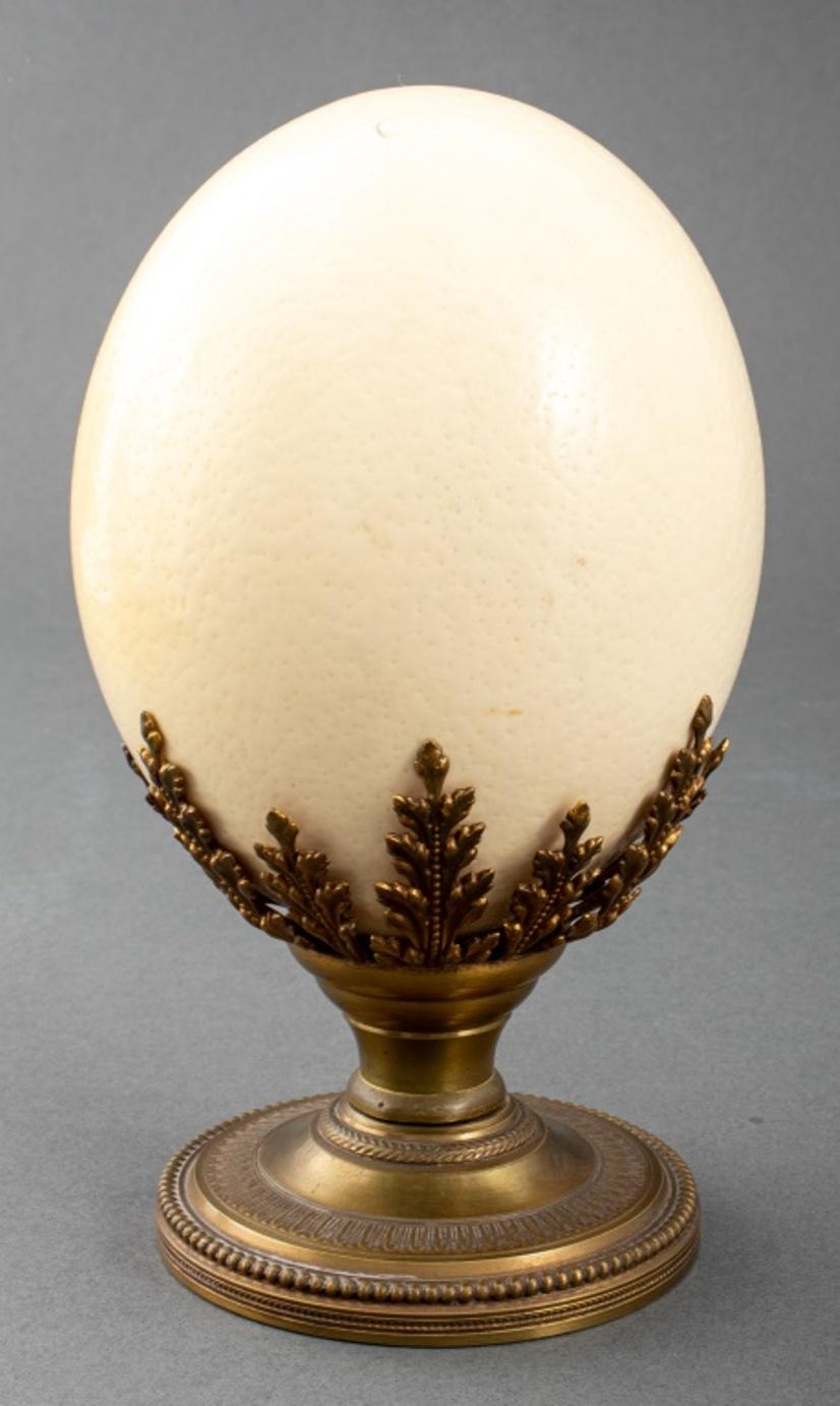 Ostrich egg upon a Louis XVI style brass stand with foliate motif.

Dimensions: 8.25