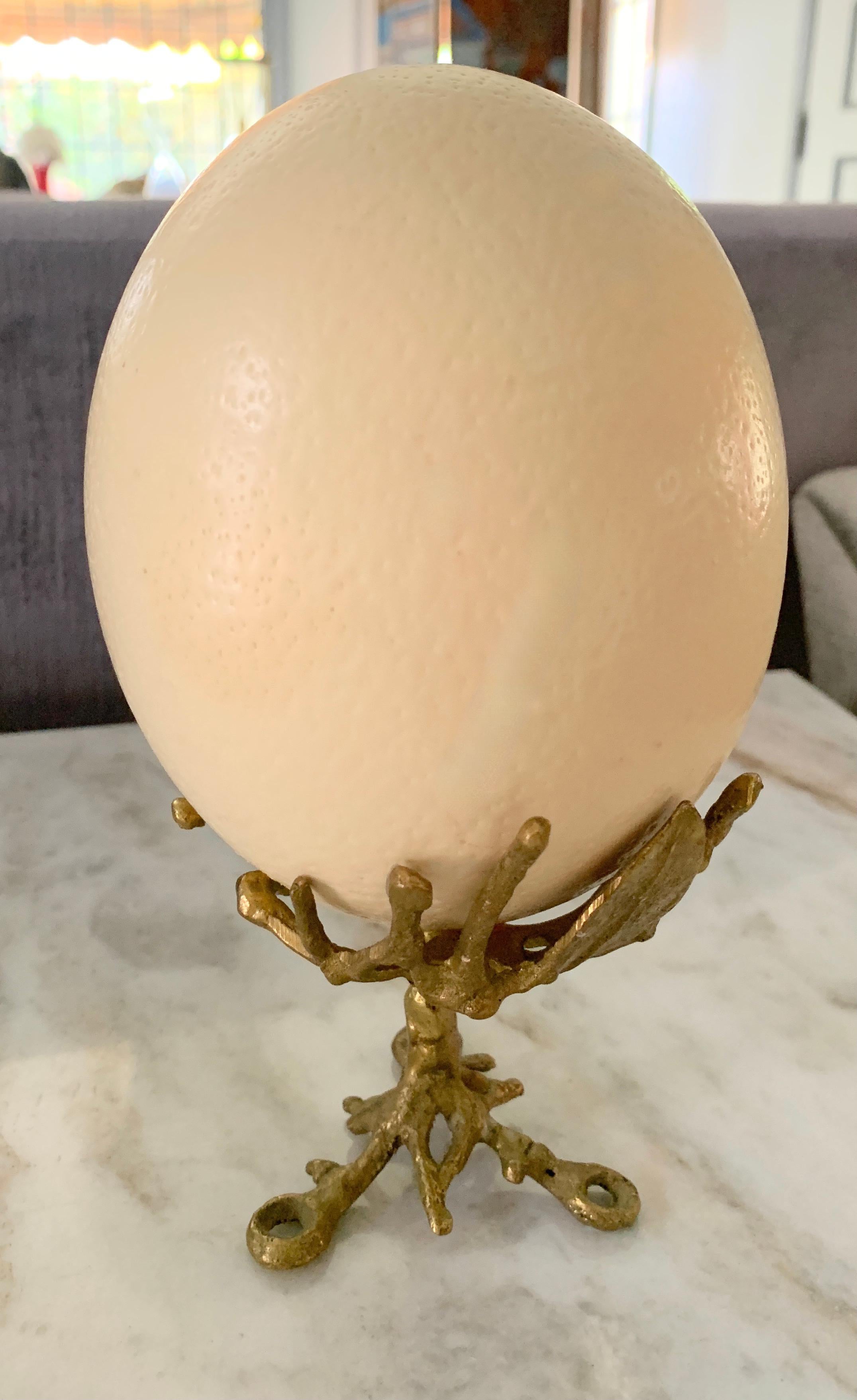 An Ostrich Egg on a gold stand that is twig like, organic and gold. A decorative piece for a shelf or mantle - simplicity and elegance.