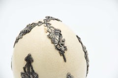 Ostrich egg resting on three silver support feet