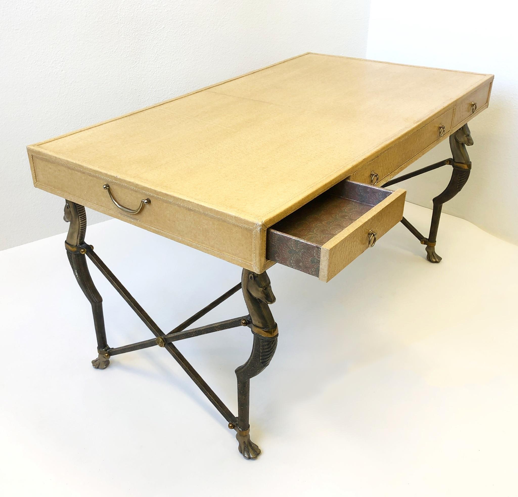 Glamorous three drawer Campaign desk designer by Marge Carson in 1999.
The desk top is covered with faux ostrich embossed leather and the four horse leg frame is constructed of aluminum with brass details. 
In great condition with minor wear