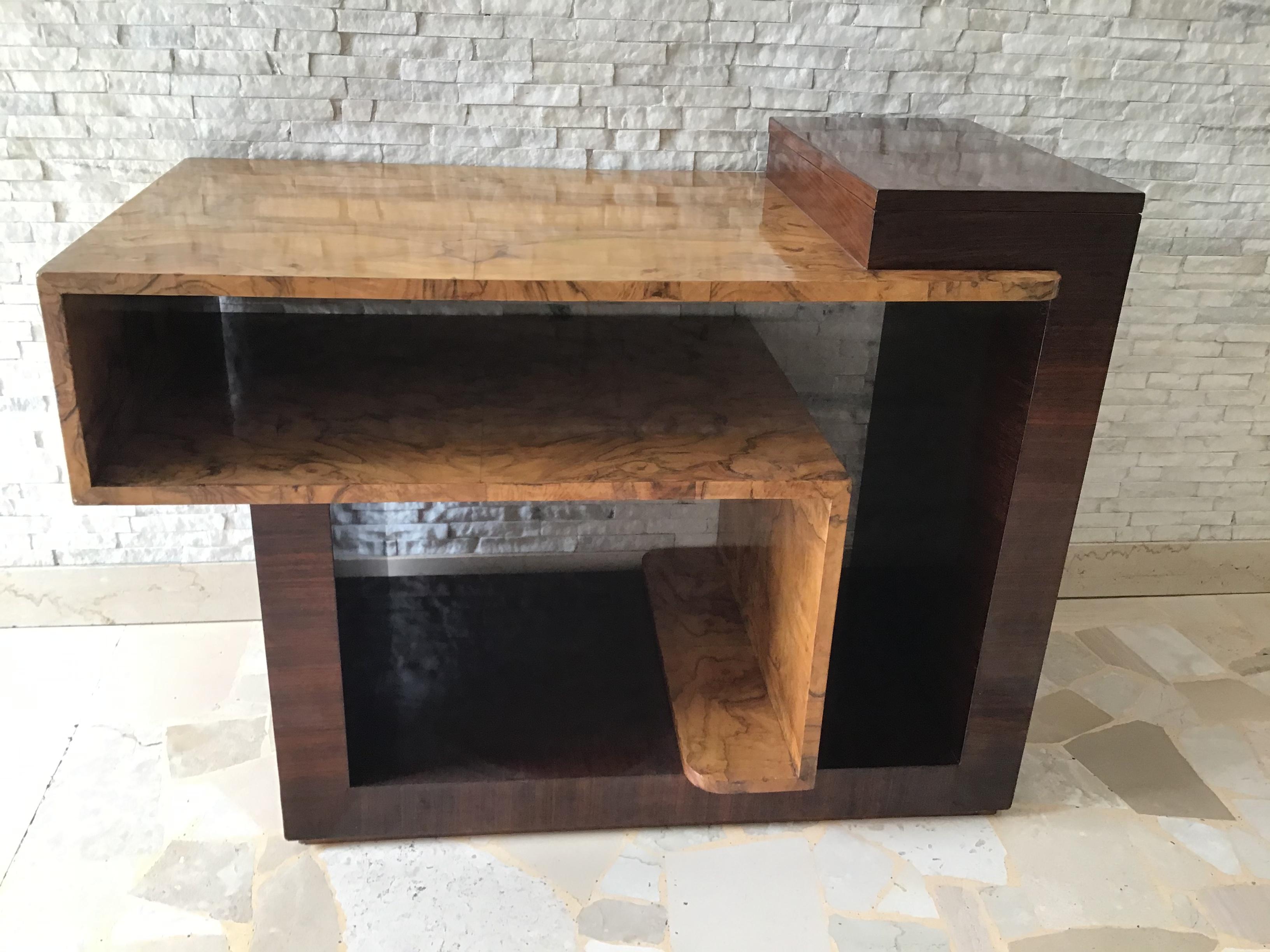 Eccezionale Tavolino con un contenitore nella parte alta , può essere usato anche come mobile etagere da ingresso.
In legno di mogano (scuro) , e radica di olmo (chiaro).
E stato lucidato a tampone.
