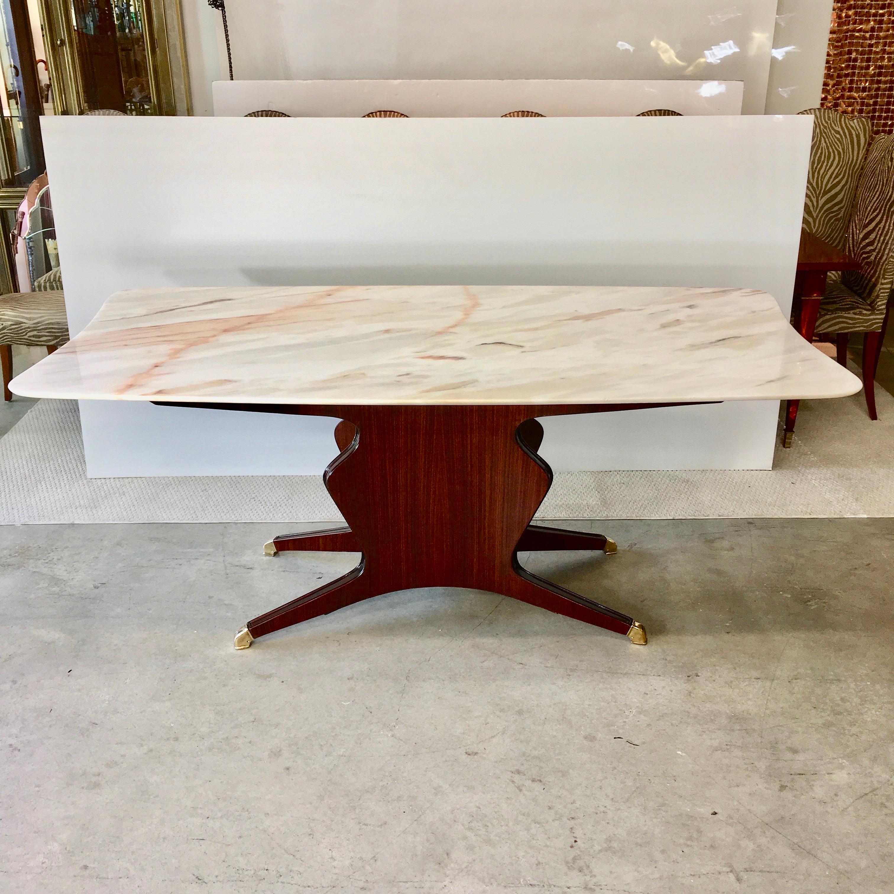 Elegant vintage Italian dining table designed by Osvaldo Borsani in 1951.
Boat shape rectangular marble top with free-form fish tail ends supported by under board on a sculptural vase-form base in richly hued polished mahogany, elevated on four