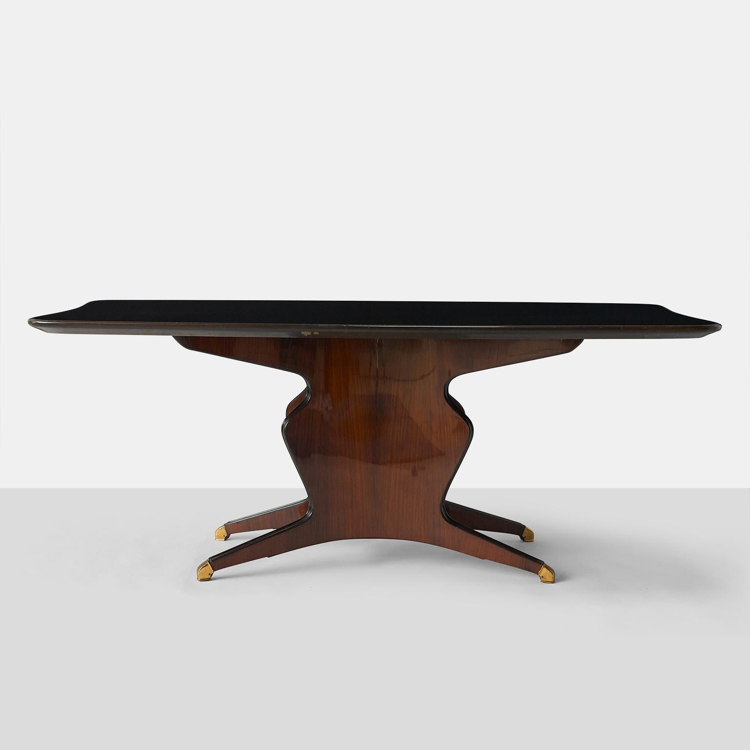 A glass topped dining table by Osvaldo Borsani. The glass insert is black painted over a rosewood base with brass toe caps. 

 