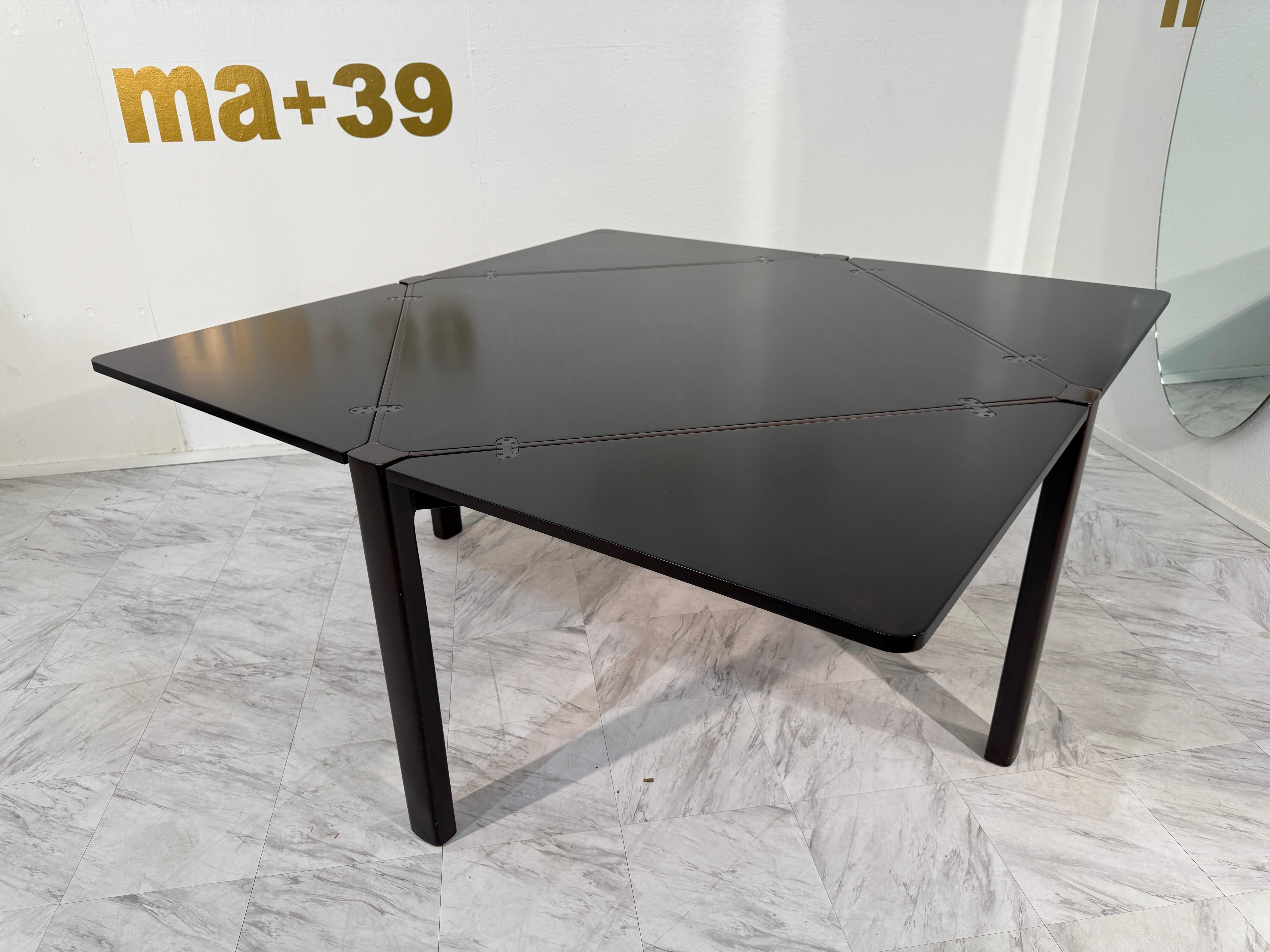 Un sofisticato tavolo da pranzo allungabile italiano del Mid-Century Modern realizzato in legno di palissandro riccamente venato. Il tavolo presenta un caratteristico piano geometrico formato da pannelli triangolari incernierati, che creano un