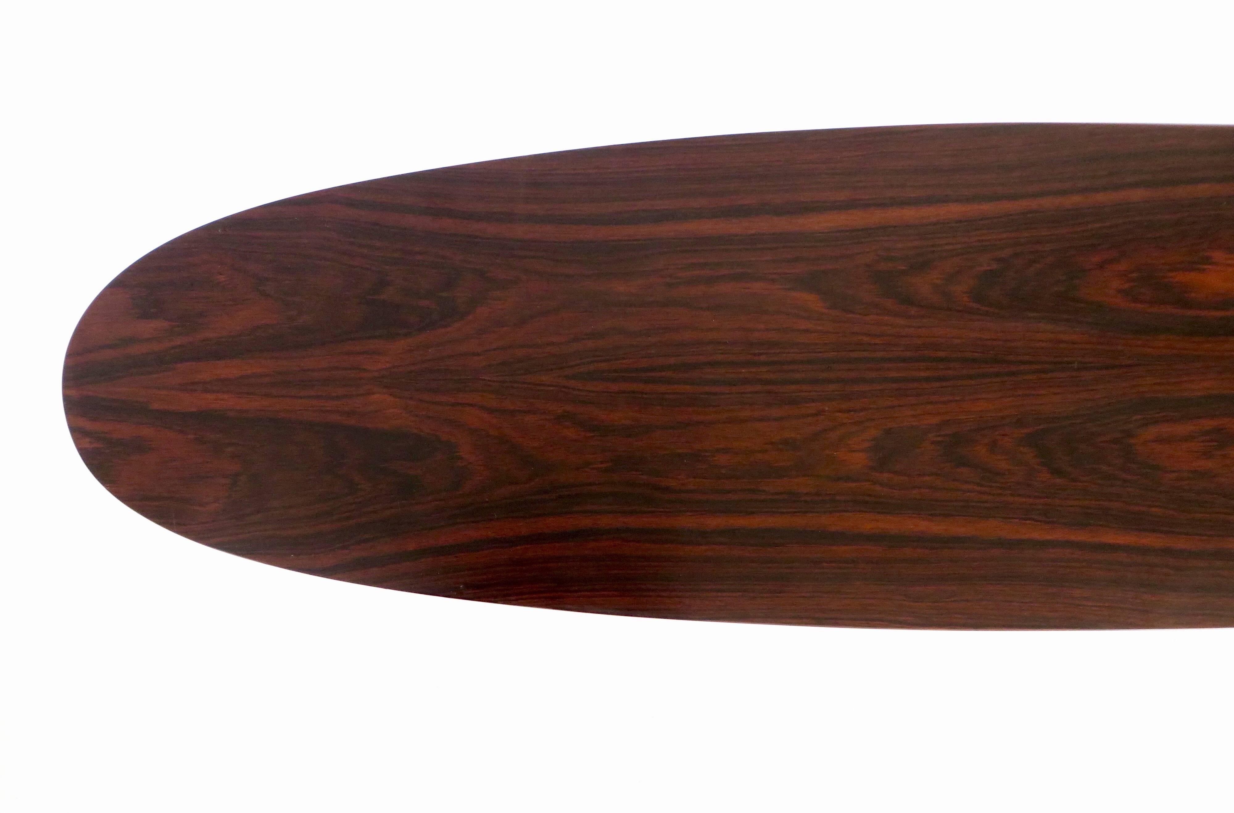 A beautiful flamed mahogany surfboard shaped coffee table by master Italian designer Osvaldo Borsani for Tecno. Delicate black metal legs on tripod feet terminating on a brass ball, circa 1960. 

Measures: 59