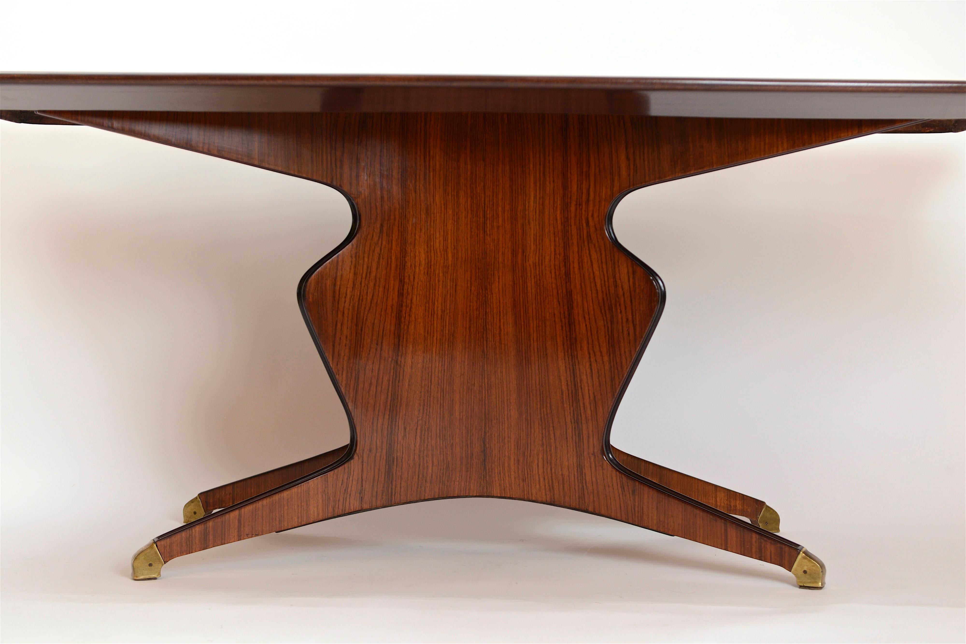 A beautifully veneered rosewood and mahogany dining table by Arredamenti Borsani Varedo, Italy, circa 1950. The wonderful curvature and elegant lines of this table are complemented by the original gold back-painted glass insert. Comfortably