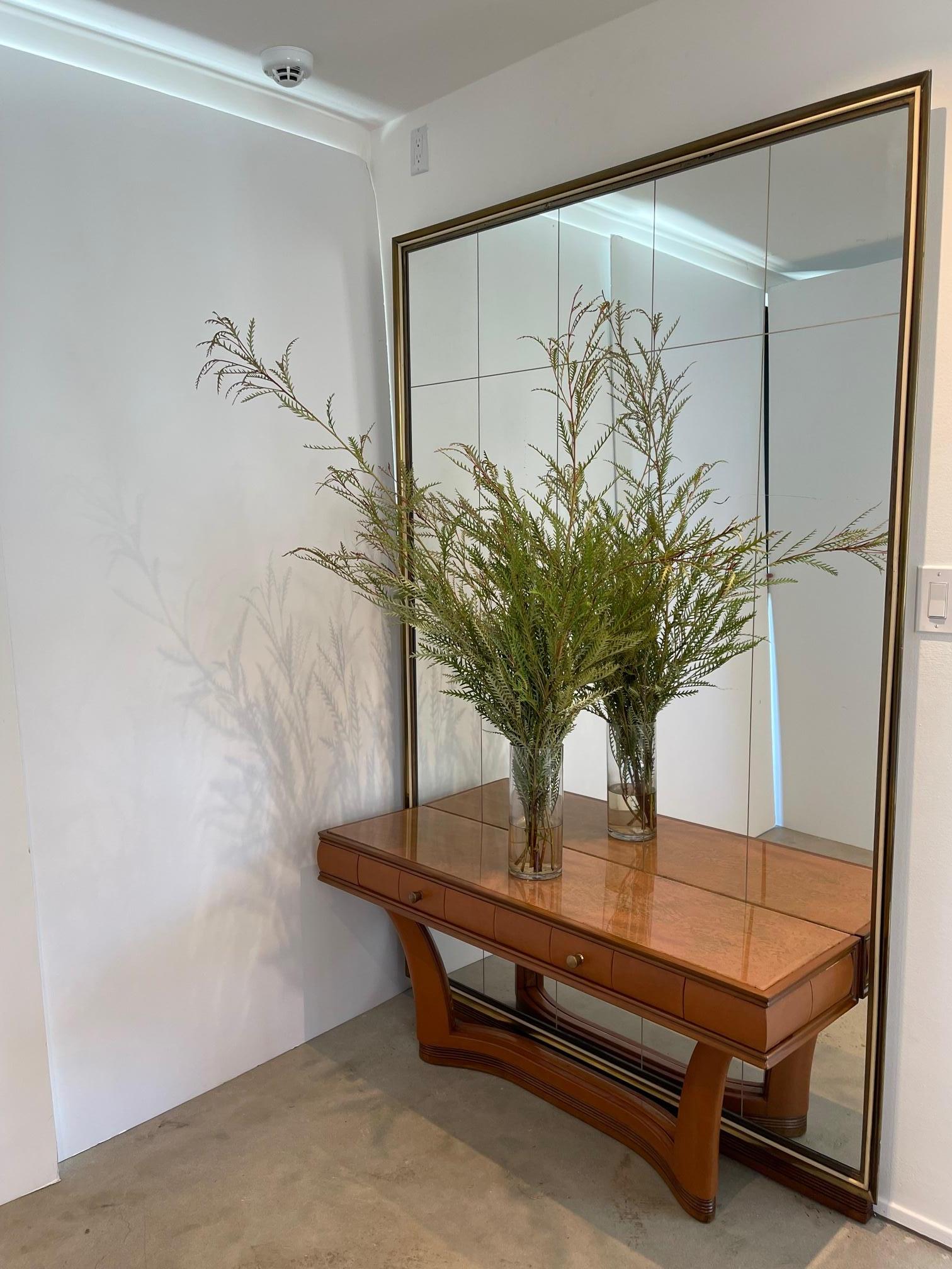 Une œuvre incroyable d'Osvaldo Borsani - 
Miroir gigantesque avec console flottante en cuir à 2 tiroirs avec quincaillerie en laiton. 
La console est attachée au miroir avec une base incurvée en noyer sculpté et orné. 
Le miroir a un cadre en