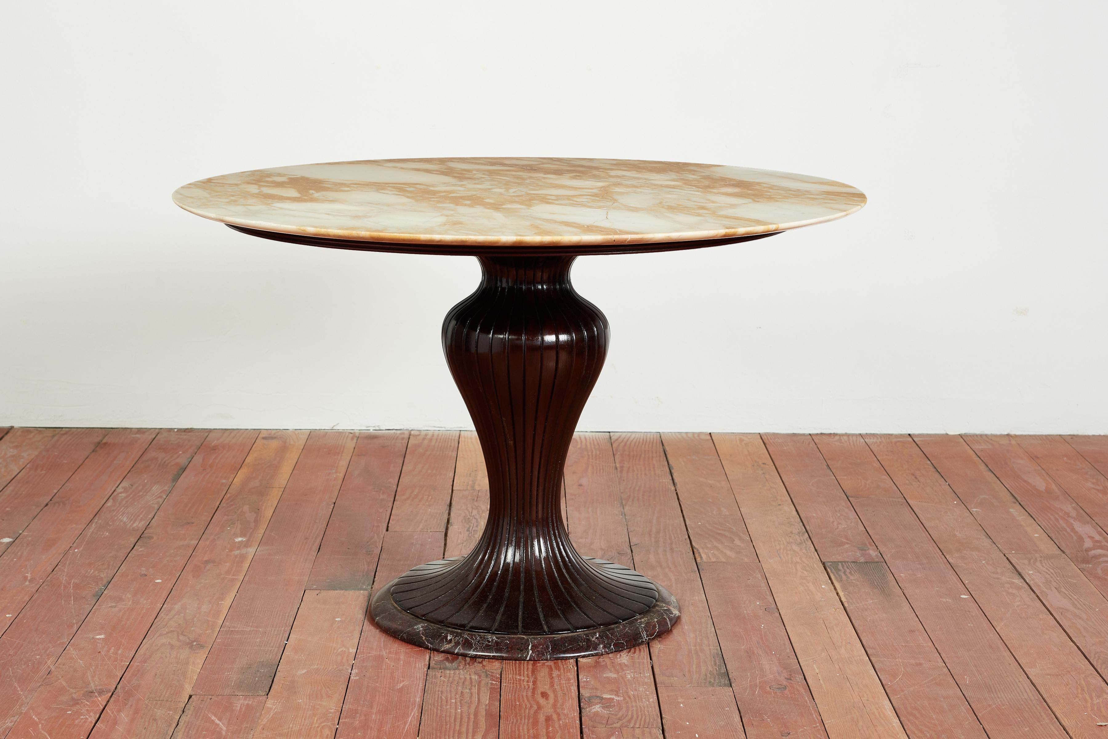 Osvaldo Borsani center table with scuptural carved wood pedestal base sitting on circular marble. 

Original marble top has beautiful coloring - and has been repaired throughout the years. 

Cracks have been filled to look like vein within the