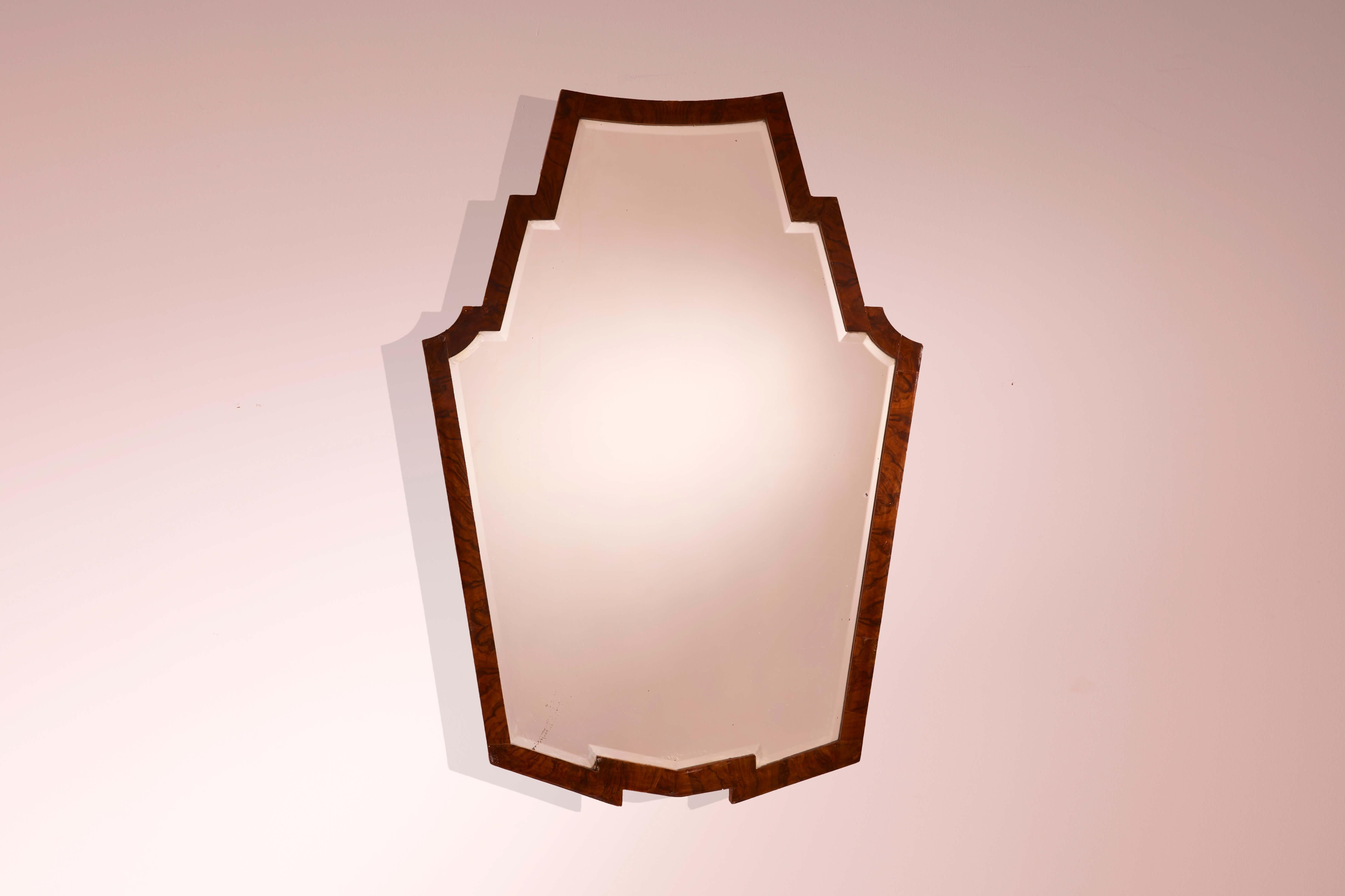 Mirror with walnut frame and shaped mirrored glass, in the style of Osvaldo Borsani, Italian craftsmanship, 1940s

With its sharp, irregular silhouette, this mirror reflects the influence of Art Deco — a style that many prominent Italian designers