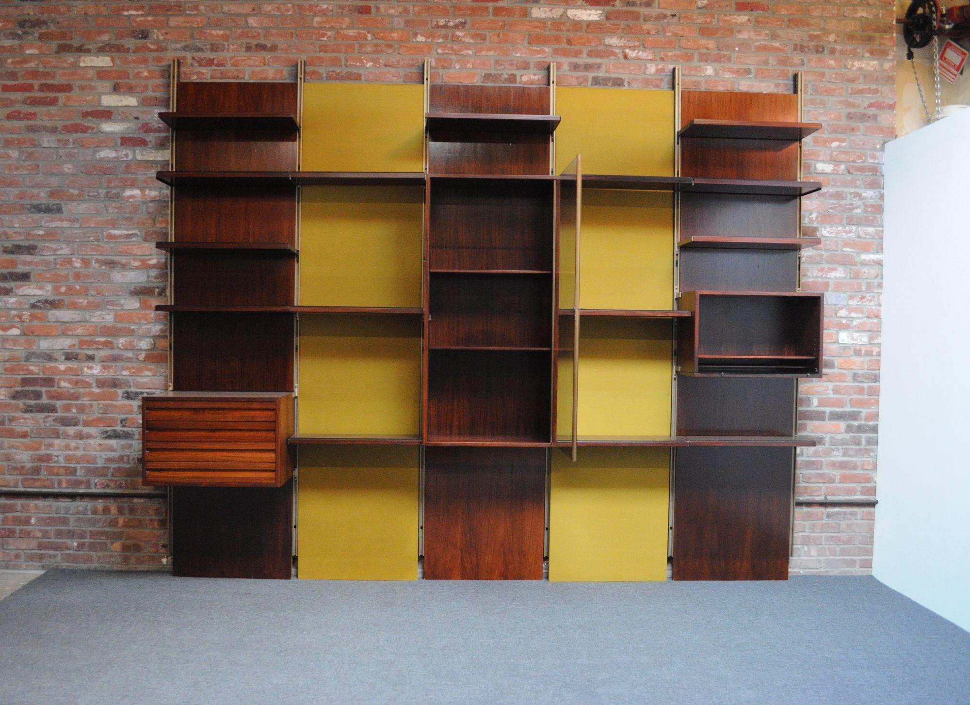 Large modular rosewood bookcase/wall unit by Osvaldo Borsani for Tecno (ca. 1960, Italy).
Composed of six gold aluminum uprights forming five bays/sections with the five original, removable panel backings in alternating ochre velvet and rosewood