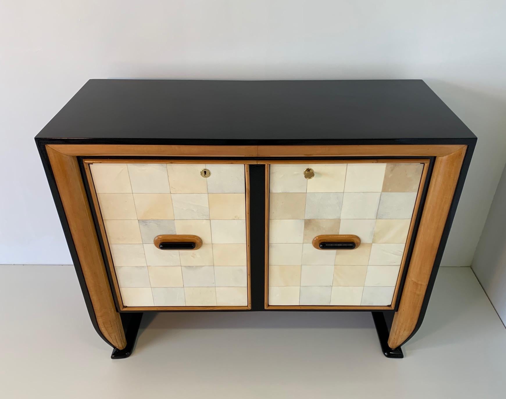 Fine cabinet attributed to Osvaldo Borsani in parchment, maple and black lacquer.
The door handles are in black lacquered and maple wood while interiors are in elegant maple.
Completely restored.
       