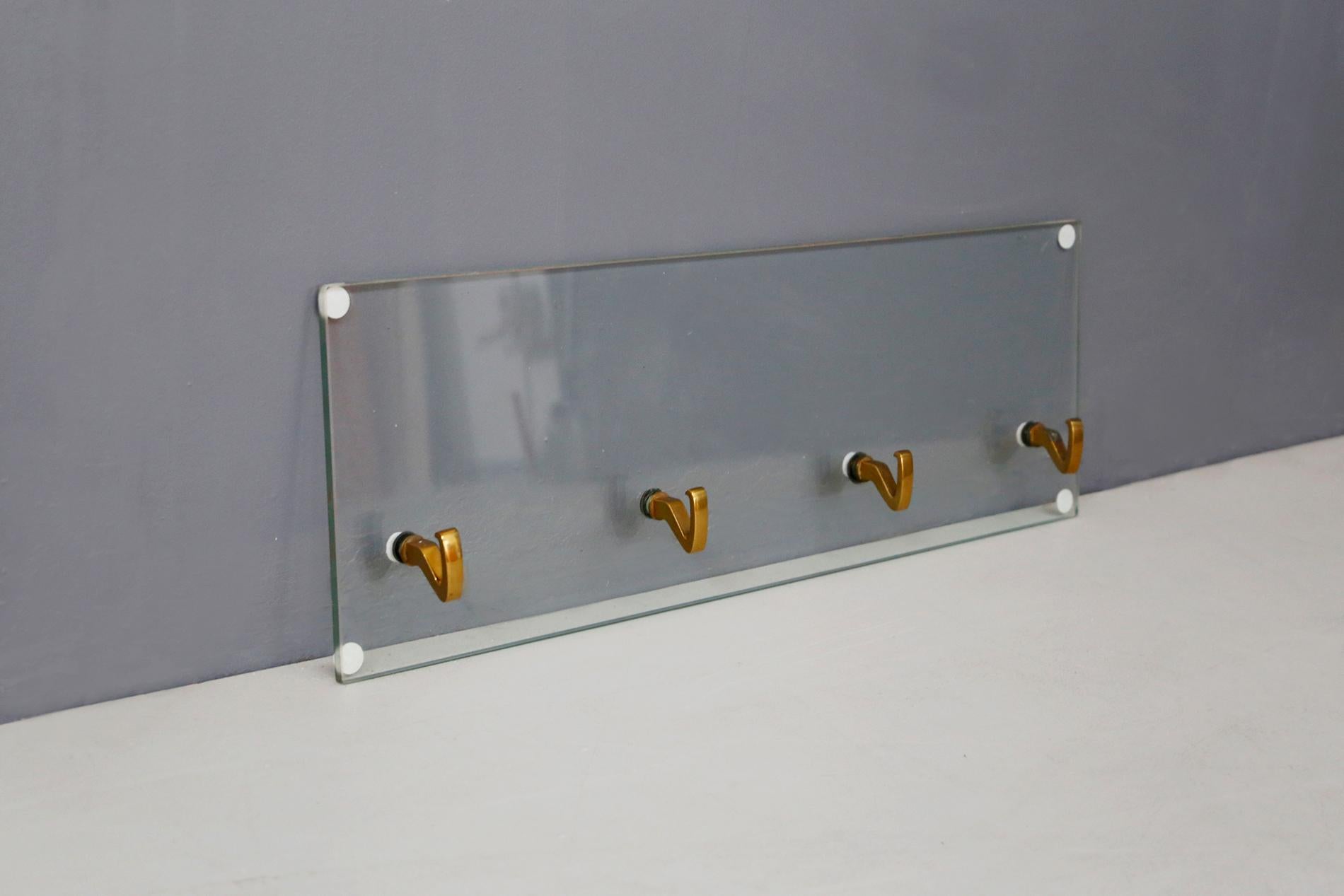 Elegant wall cloth rack designed by Osvaldo Borsani for Tecno in 1950. The hanger is in thick ground crystal with four brass hooks. It can also be used as a hat rack. The object is ideal for modern entrances or for high class offices. The hanger is