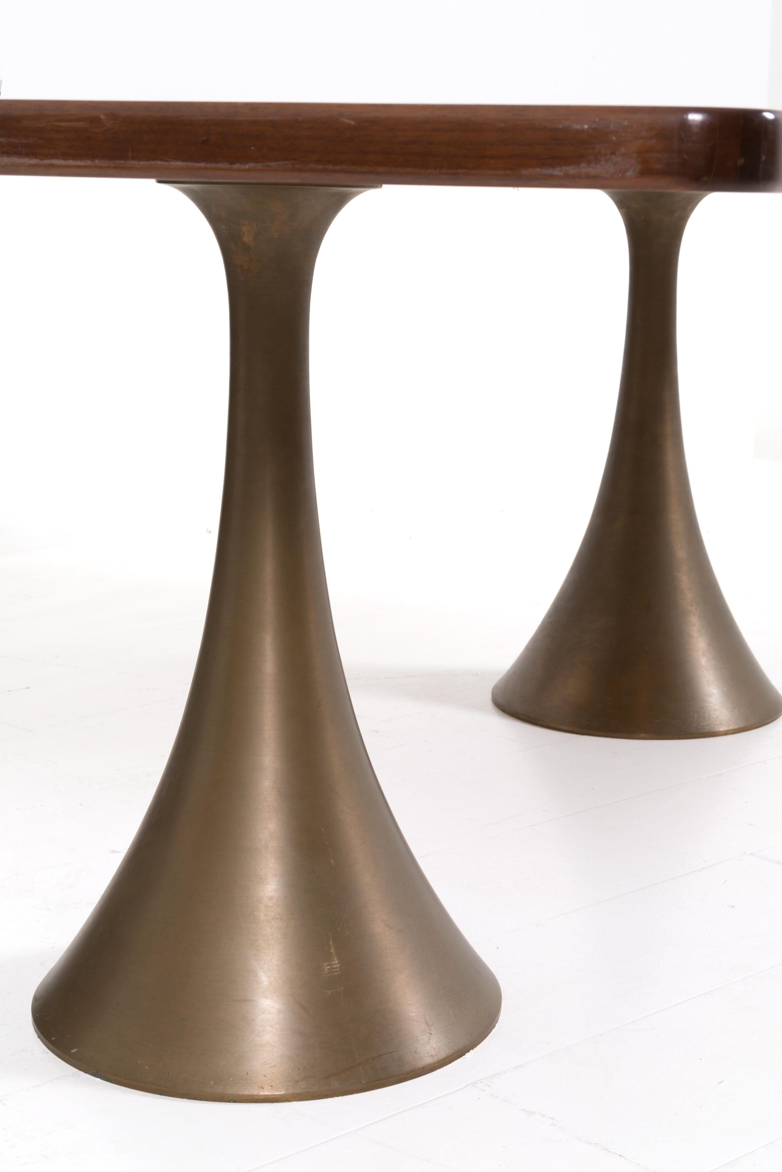 Rare and important table designed and made by Osvaldo Borsani in 1971. The table has a thick wooden top. The peculiarity and uniqueness of the table are its trumpet-shaped pedestals and supports made entirely of bronze. The importance of the table